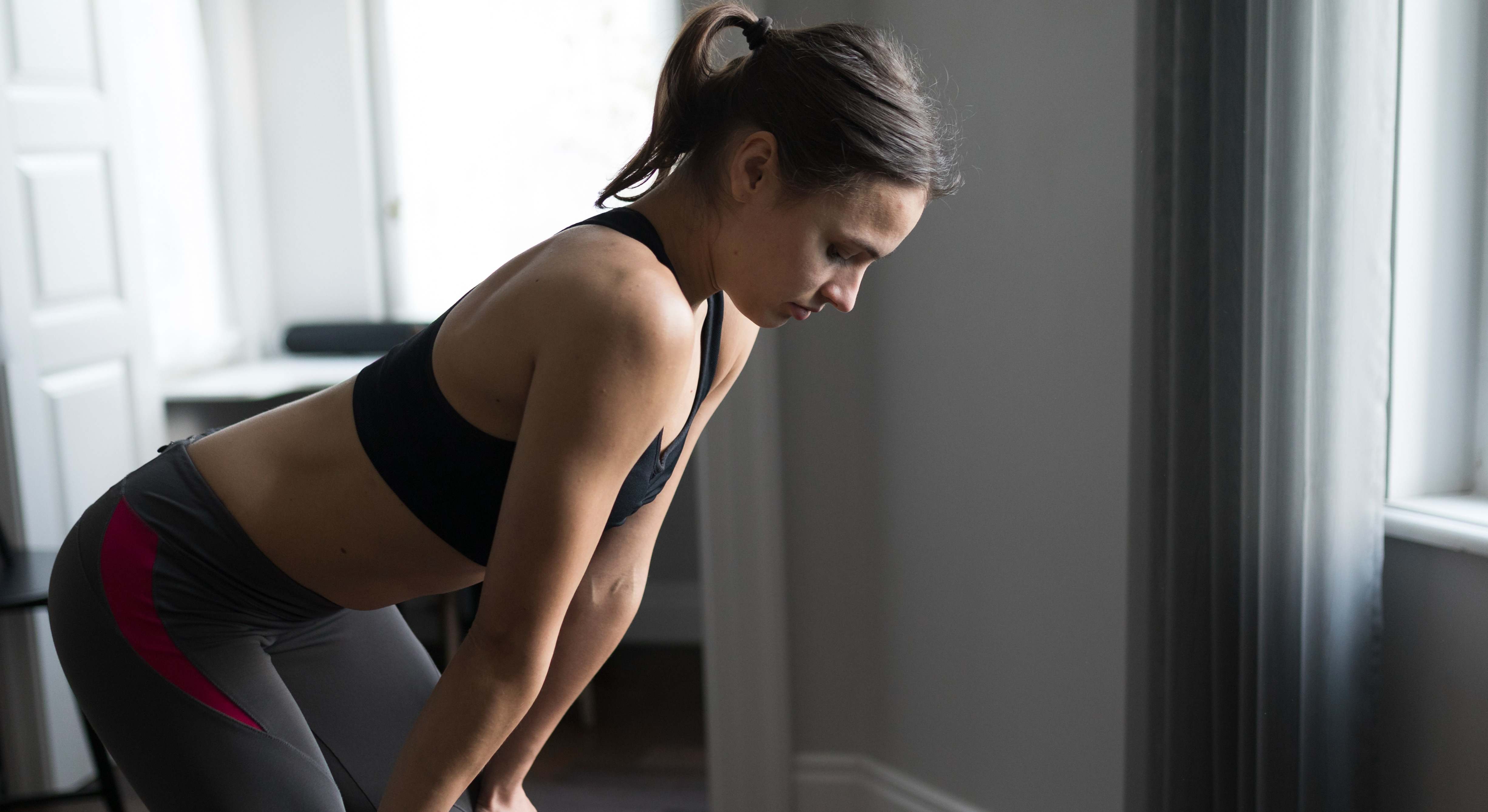 Mujer medio agachada con ropa de deporte