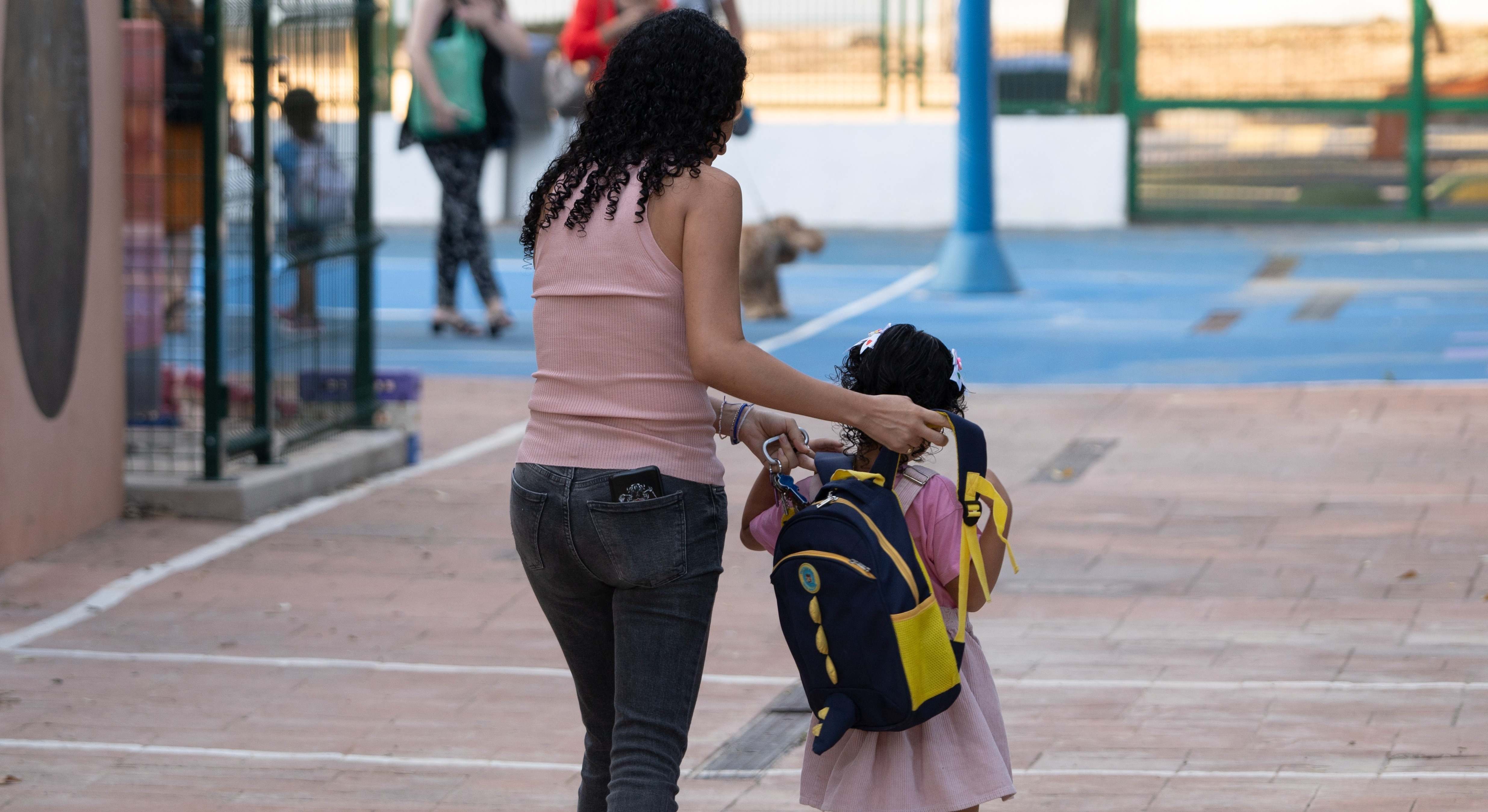 Una mujer acompaña a una niña al colegio