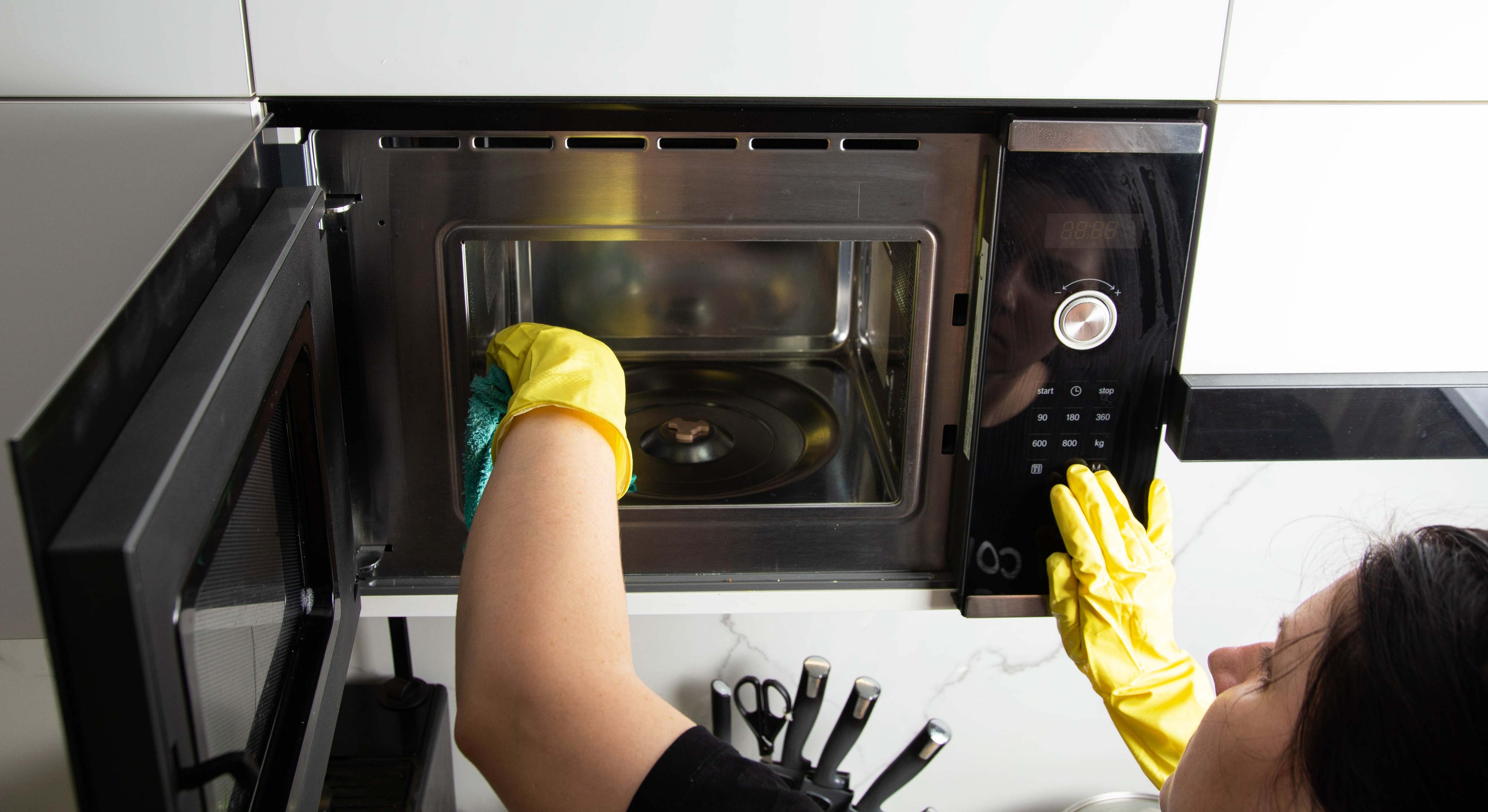 Una mujer limpia el interior del microondas. / Foto: iStock