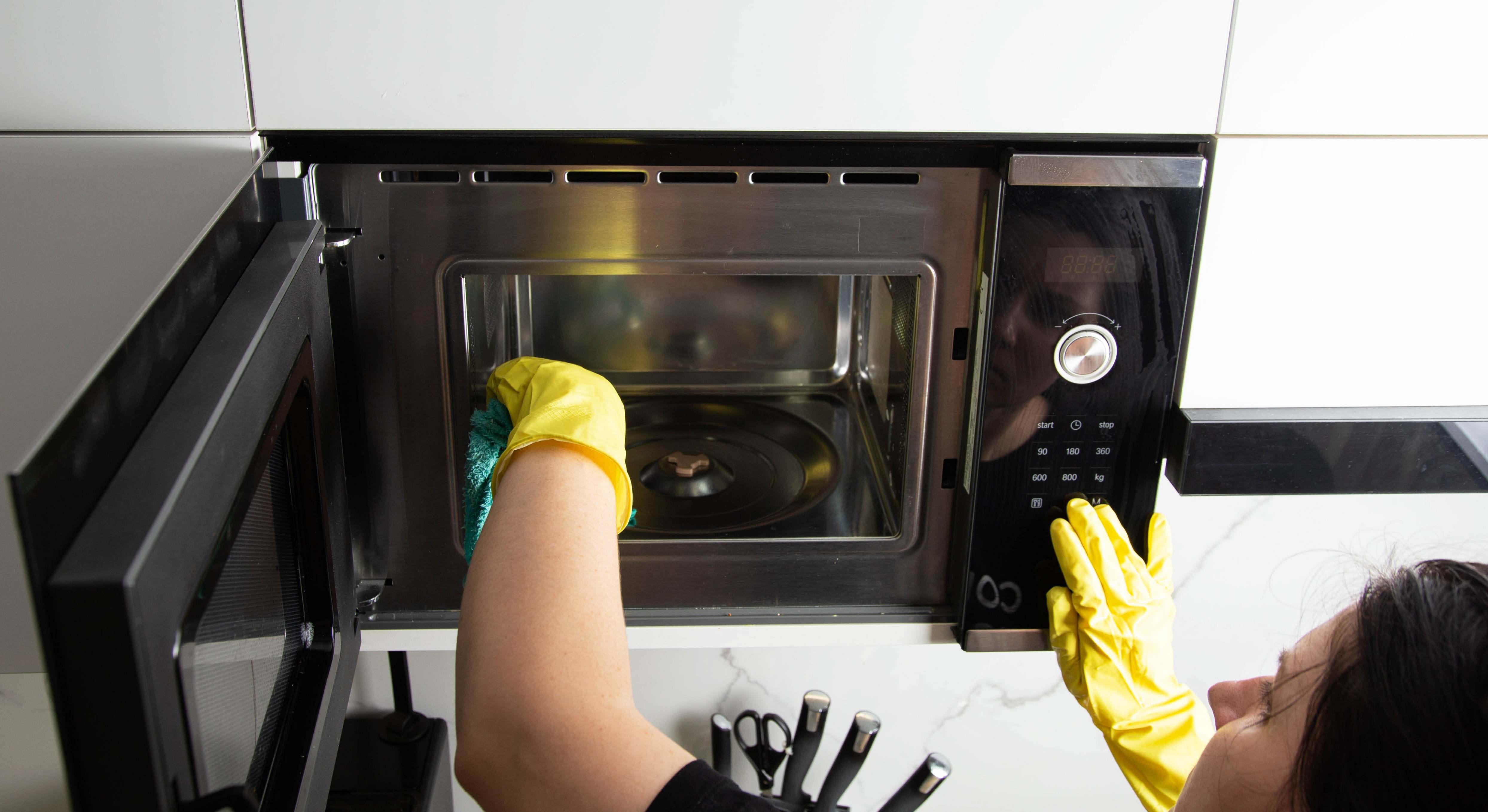 Una mujer limpia el interior del microondas. / Foto: iStock