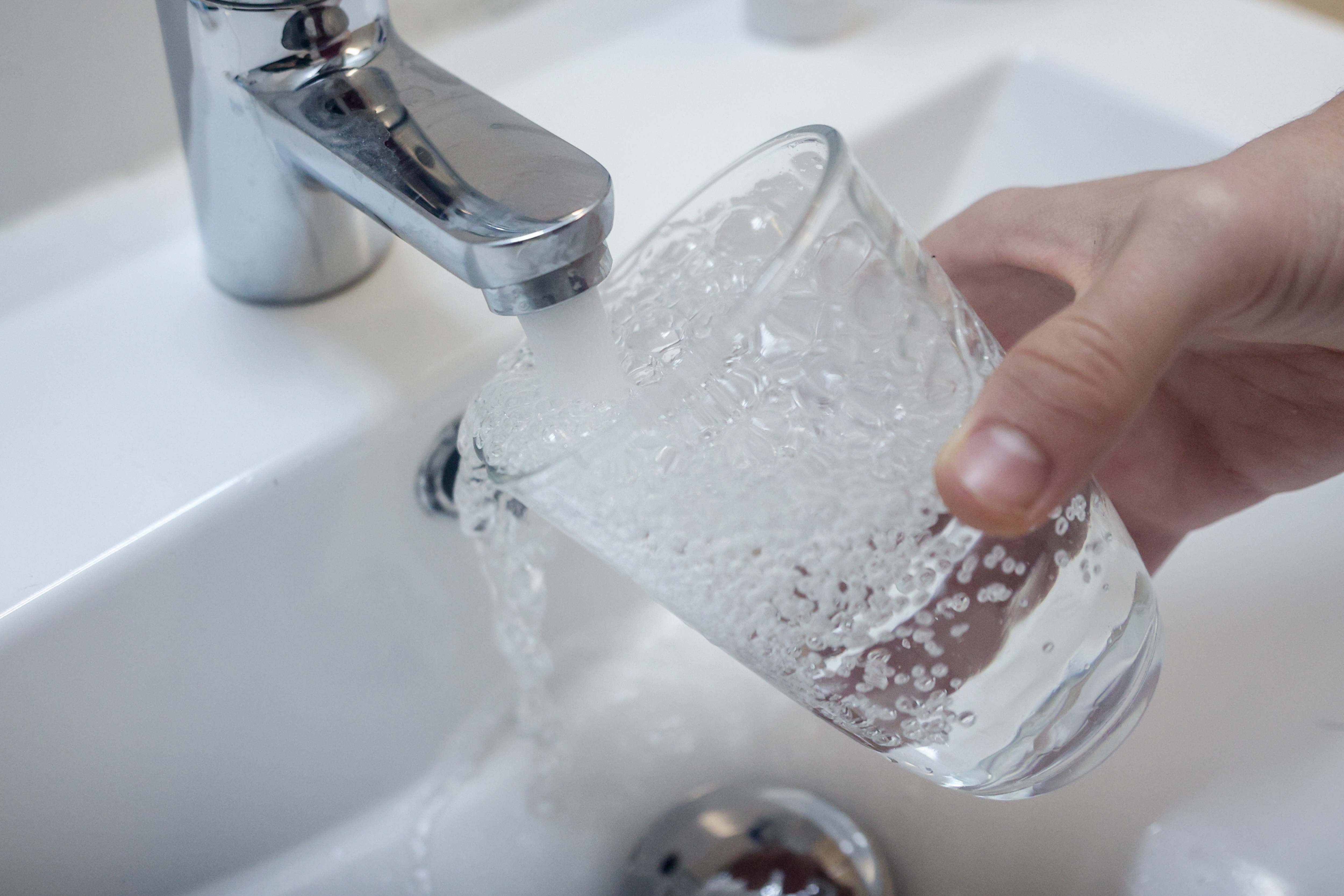 Imagen de recurso de una persona llenando un vaso con agua del grifo.