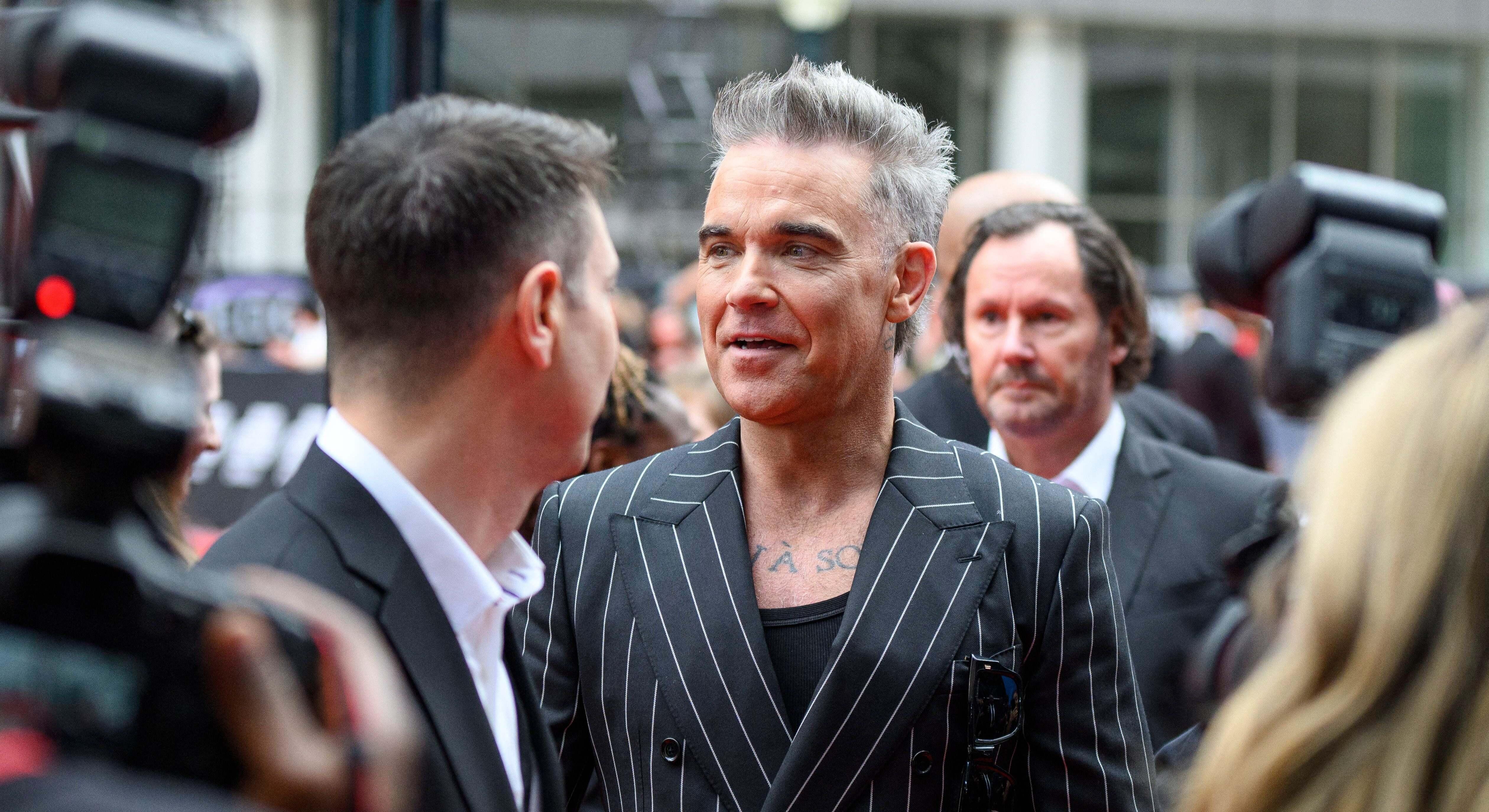El cantante Robbie Williams rodeado de gente en la calle