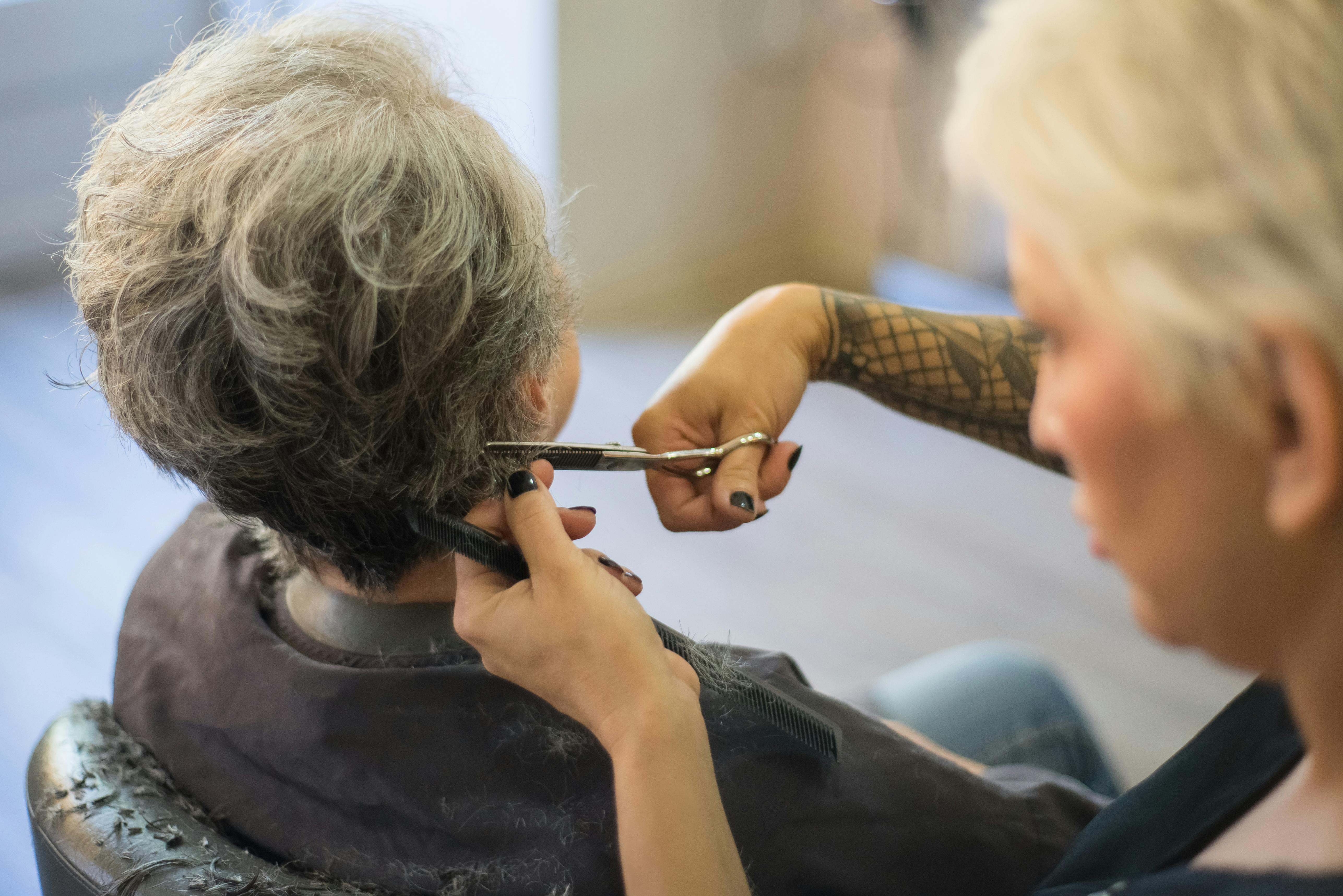 Una mujer con bastantes canas se corta el pelo