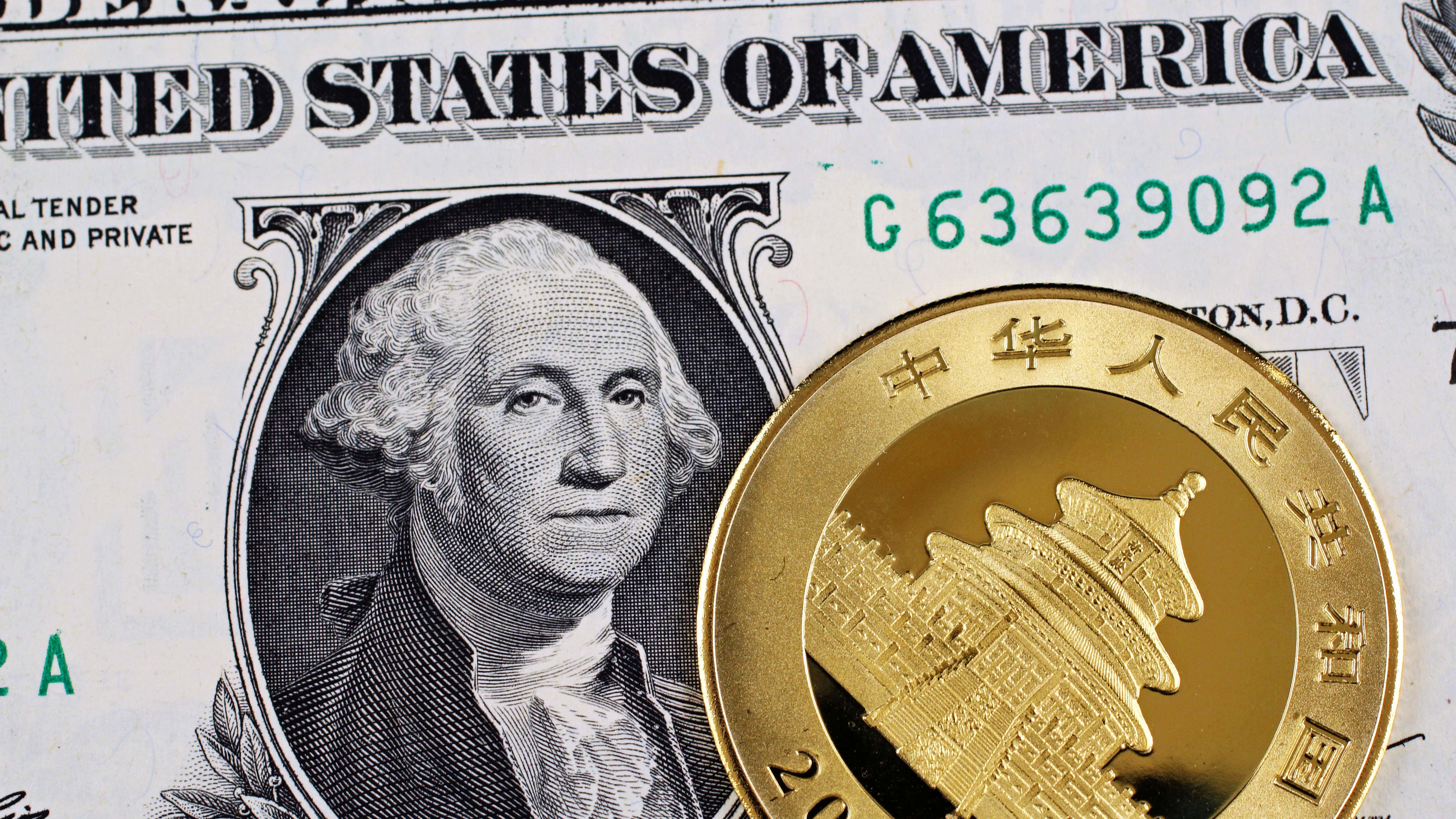 Moneda de oro china frente a un dólar (Dreamstime)