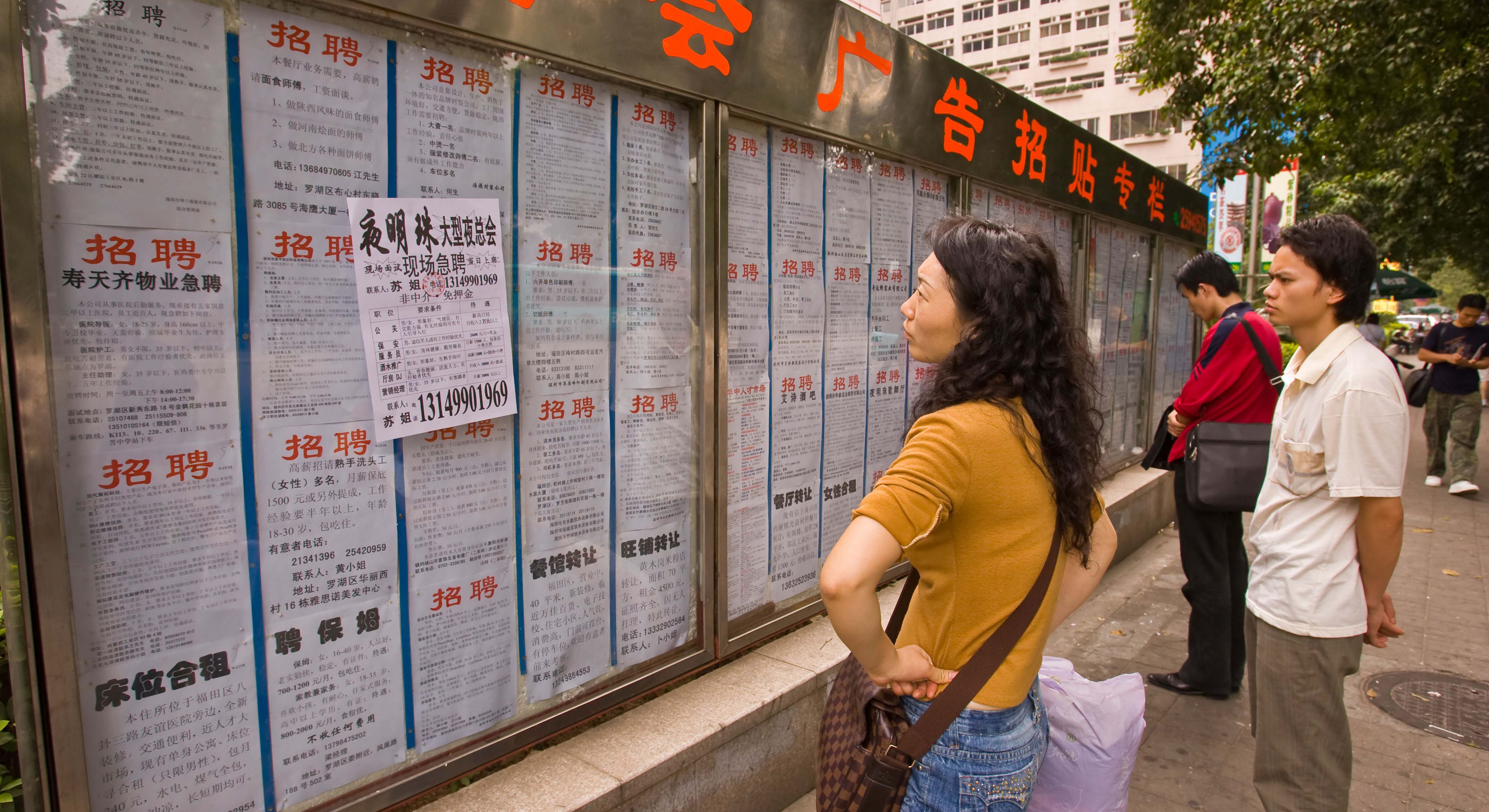 Personas mirando un tablón de anuncios de empleo en Shenzhen. Foto: Alamy