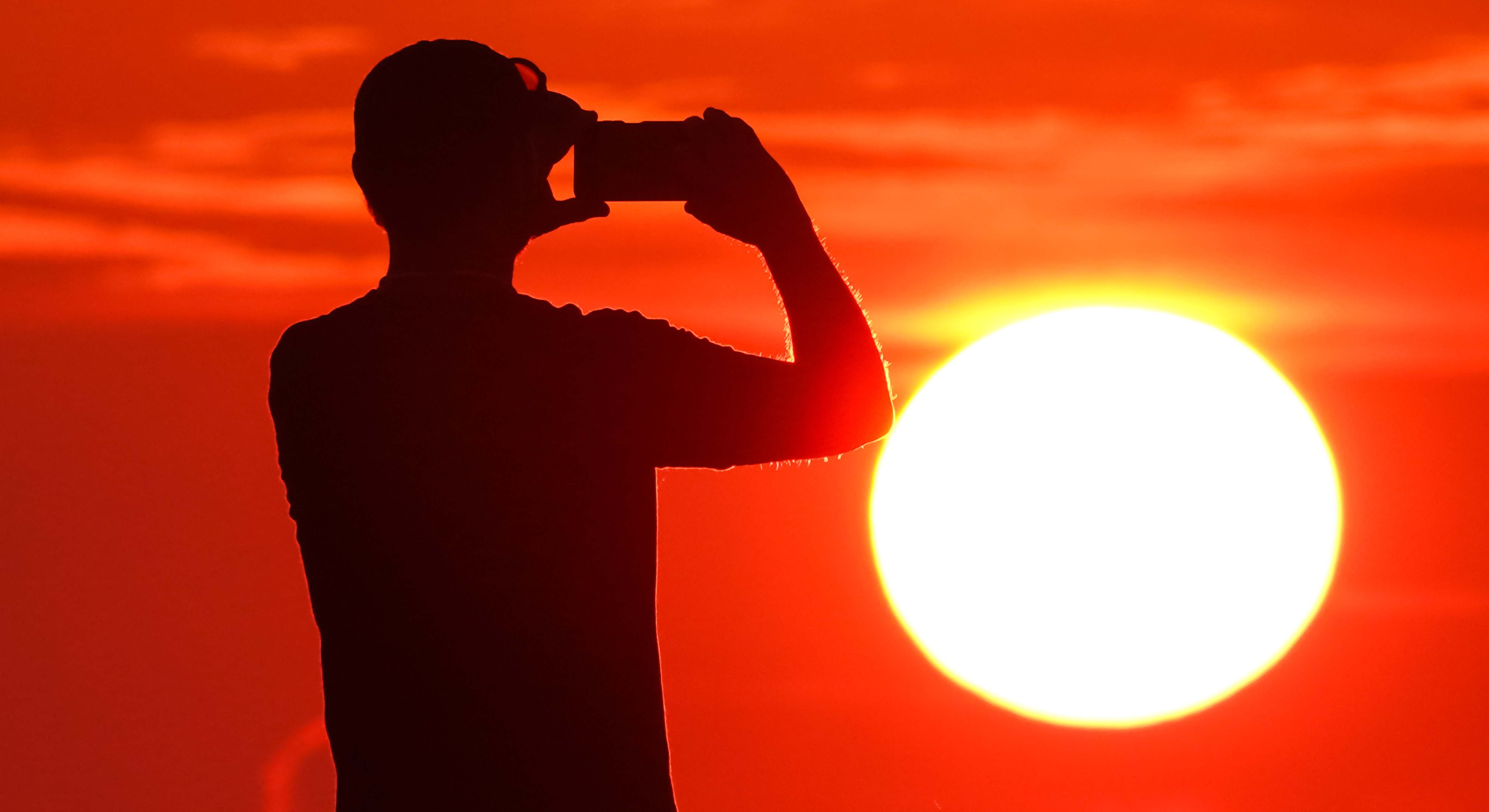 Un hombre fotografiando al sol