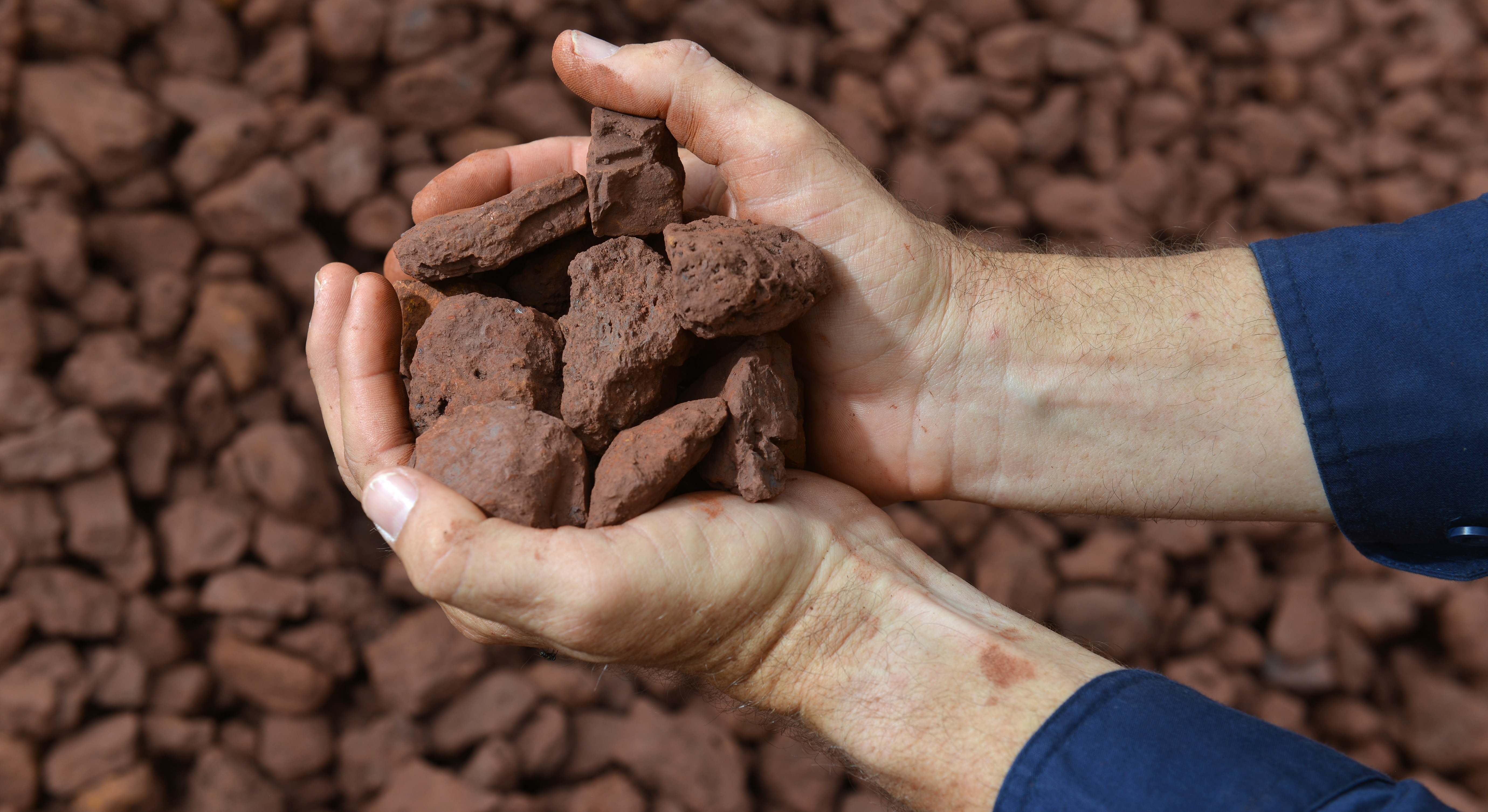 Manos sosteniendo mineral de hierro
