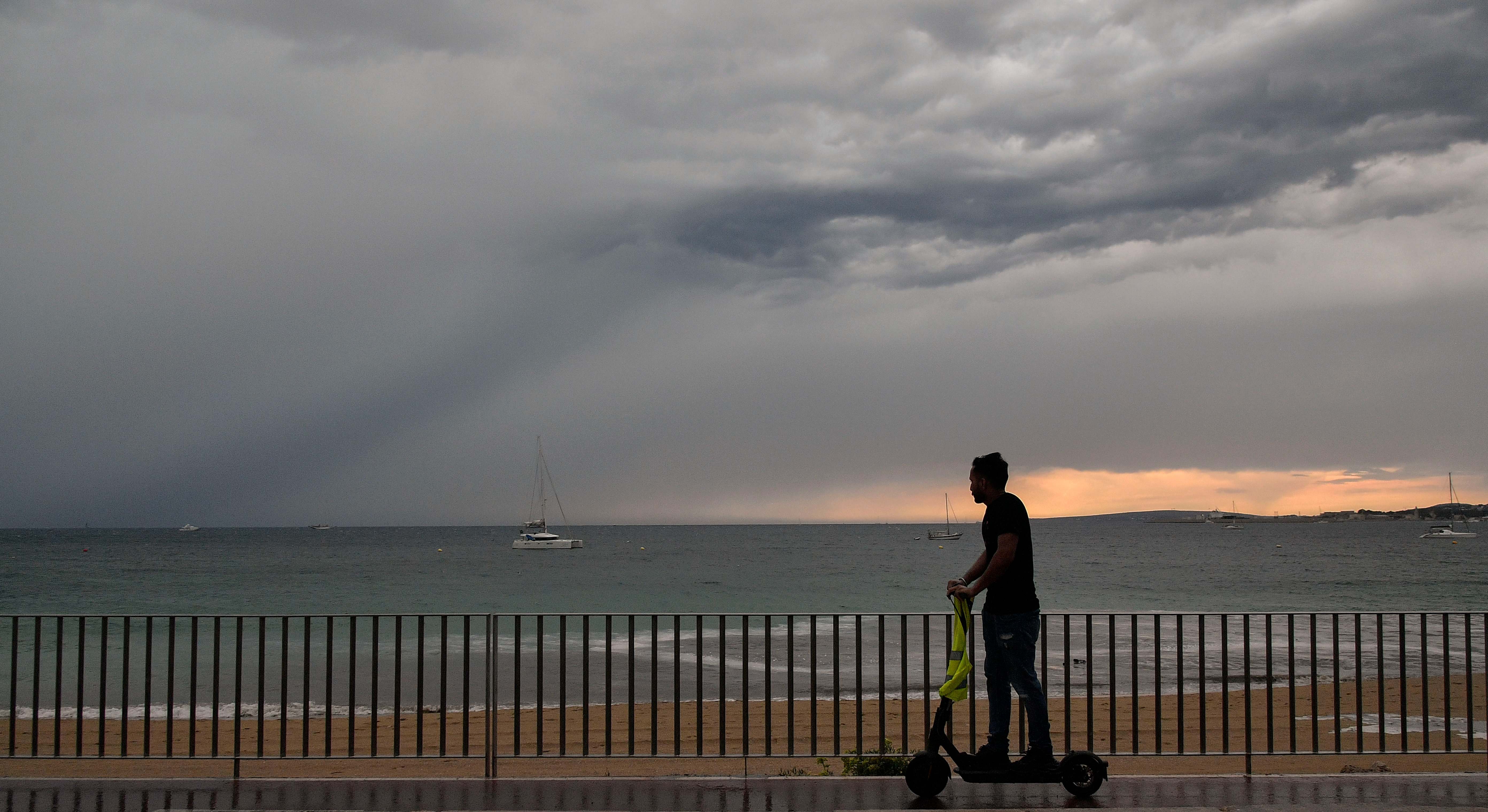 Un hombre pasea en patinete por el paseo marítimo de Palma de Mallorca