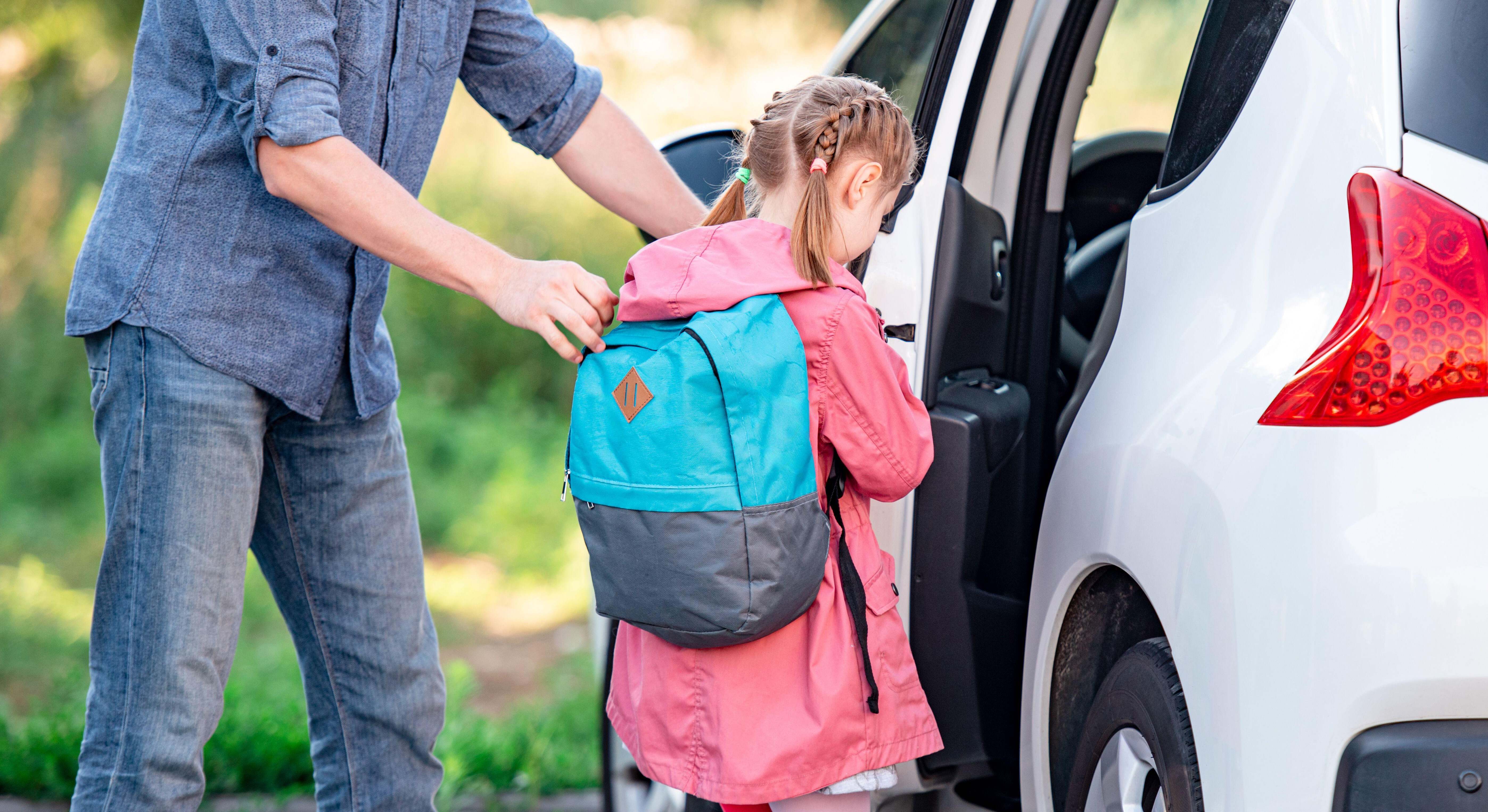 Un padre recoge a su hija del colegio y la ayuda a subir al coche
