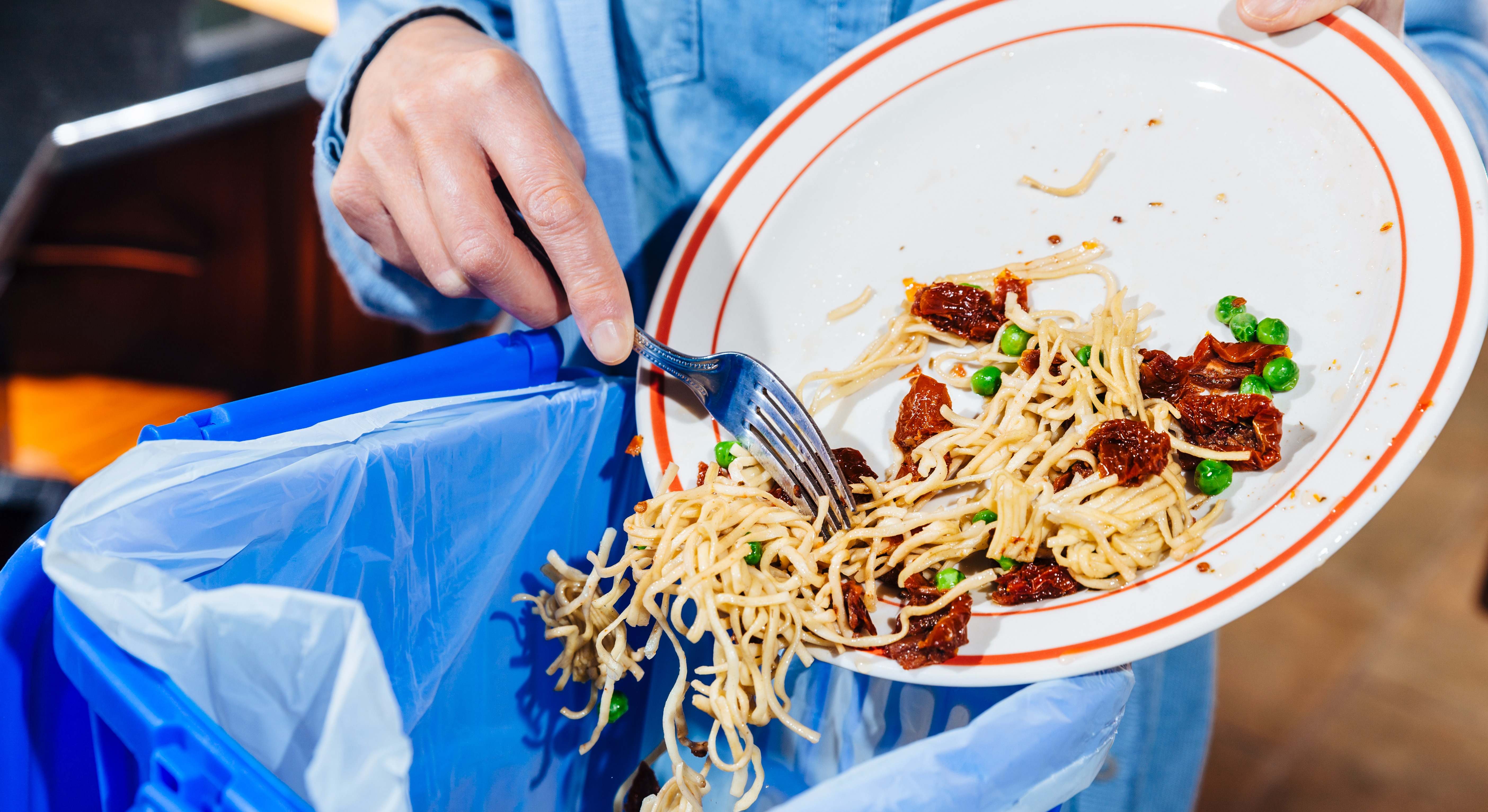 Imagen de una persona tirando comida en un cubo de basura. / Foto: iStock.