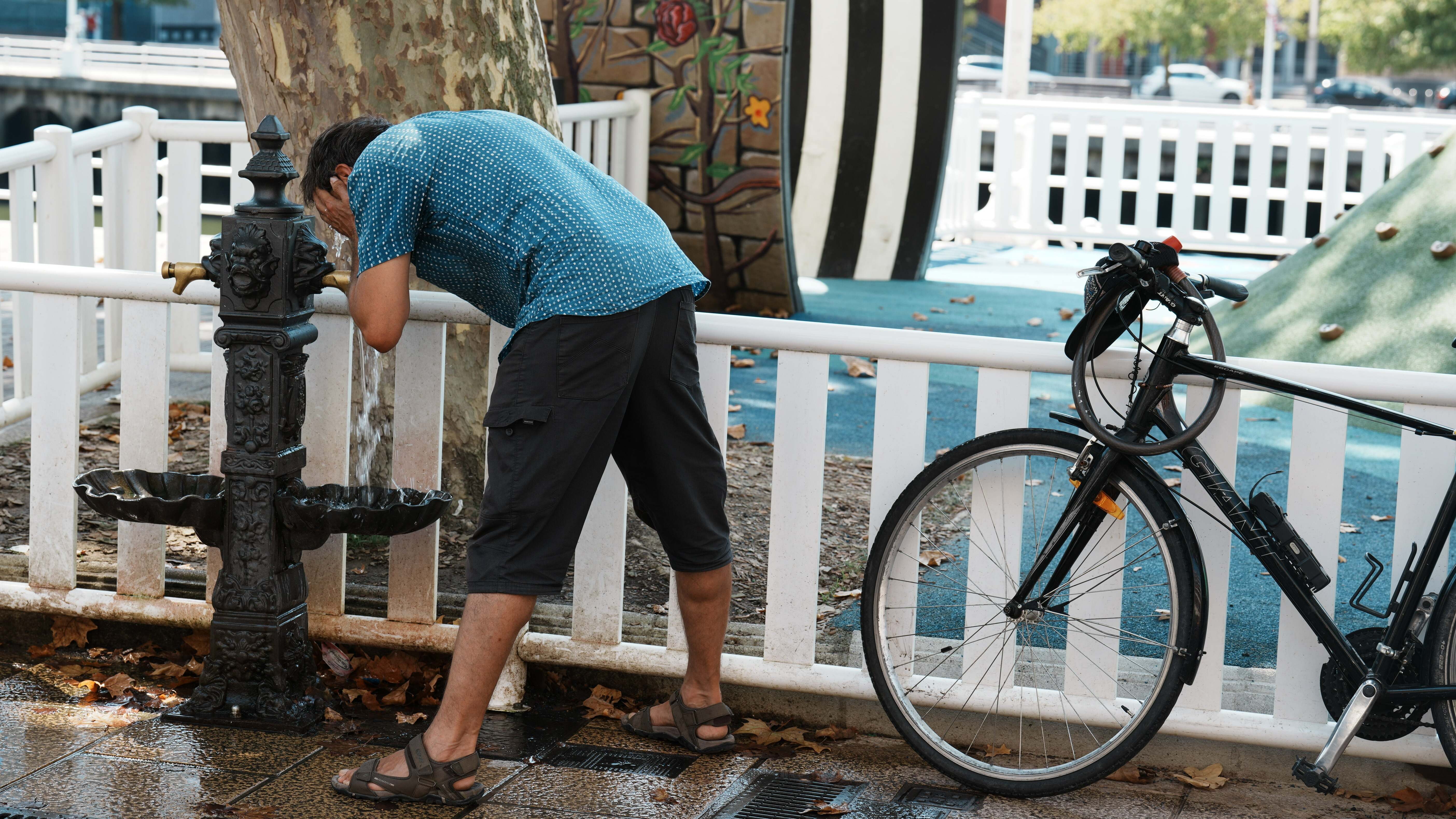 Un hombre se moja la cara con el agua de una fuente durante la cuarta ola de calor del verano, a 23 de agosto de 2023, en Bilbao