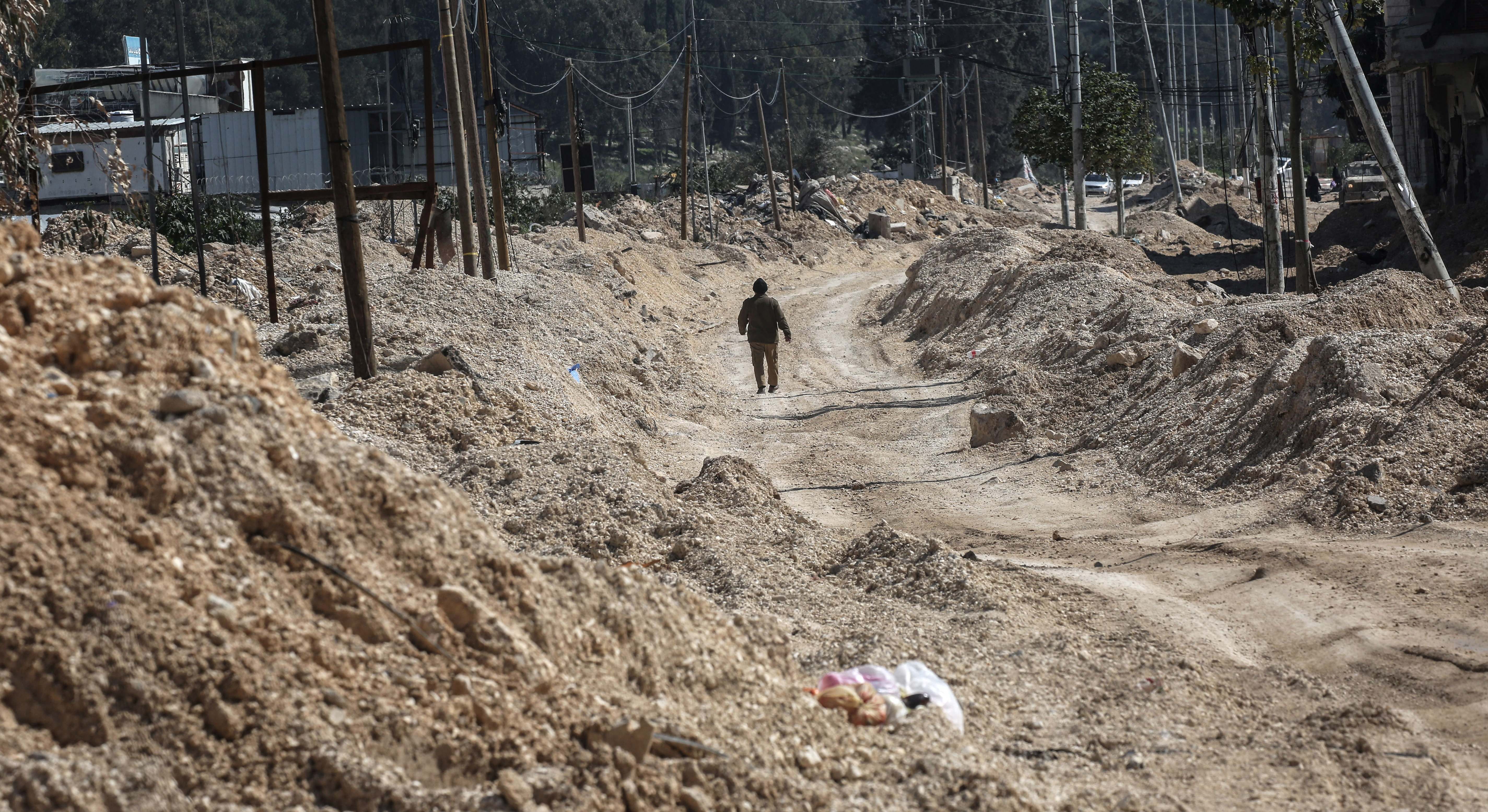 Refugiado palestino camina por una calle destruida en un campamento de Cisjordania