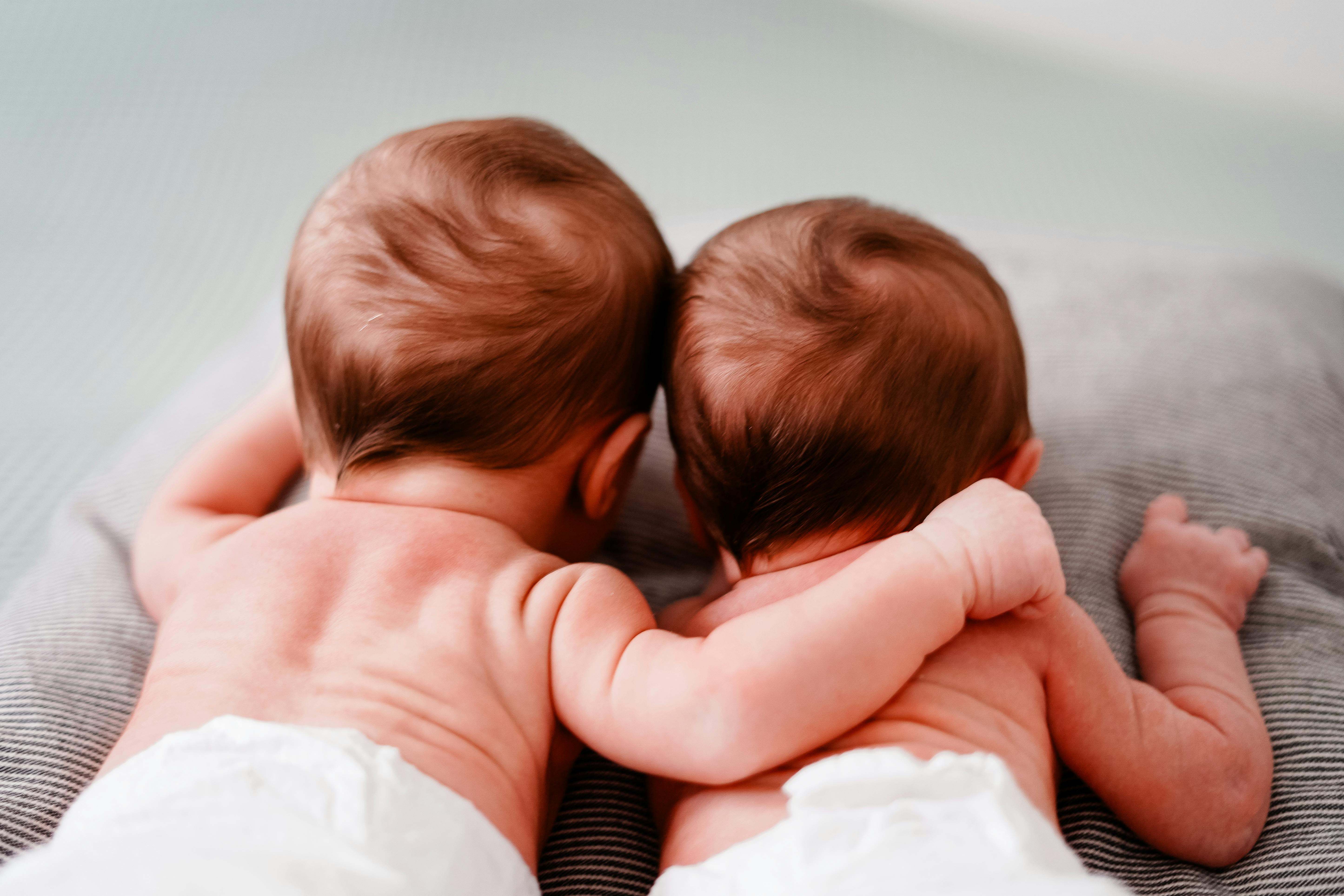 Dos bebes se abrazan mientras están tumbados en una cama