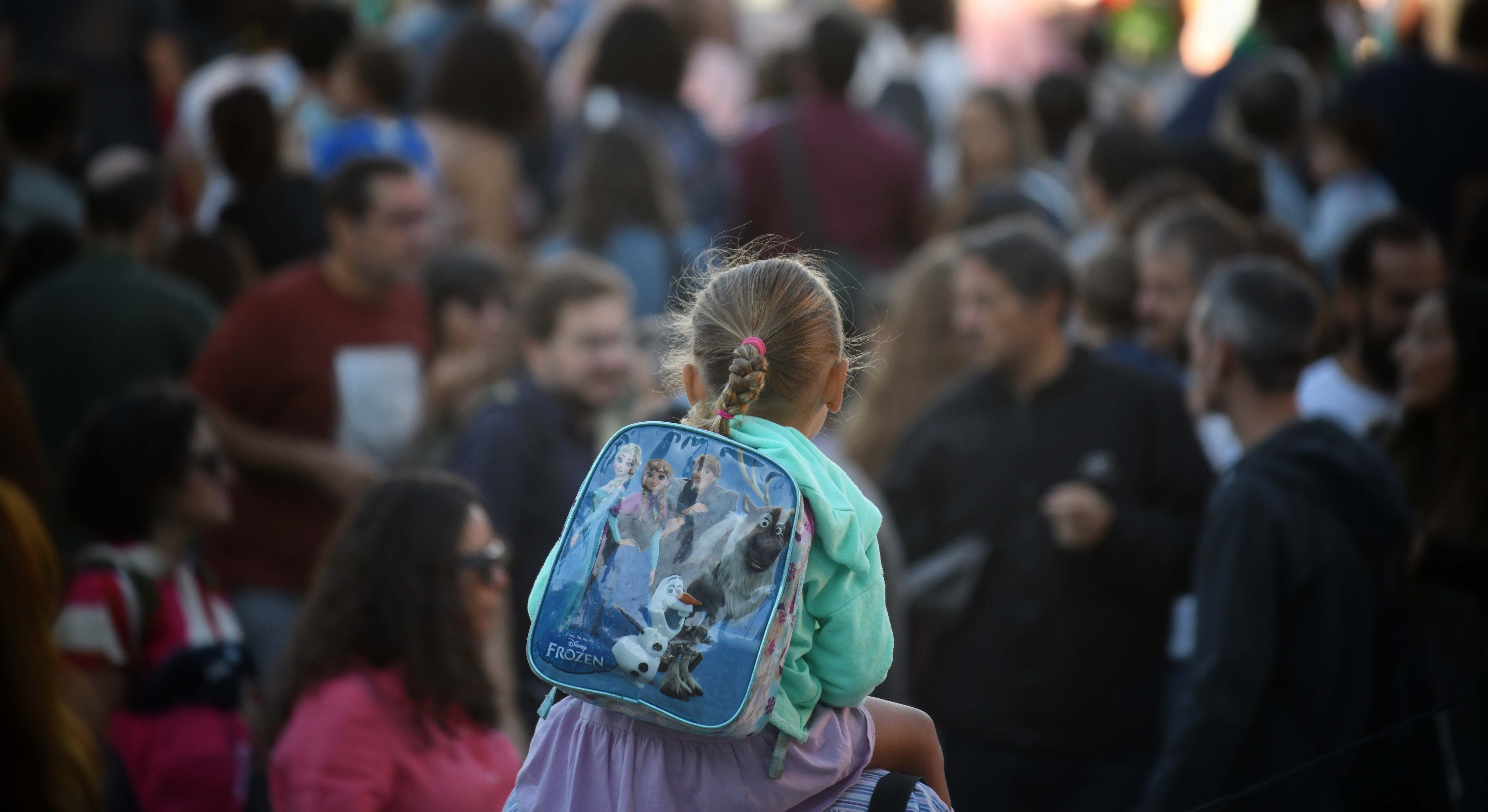 Vista de una niña subida en hombres con una mochila