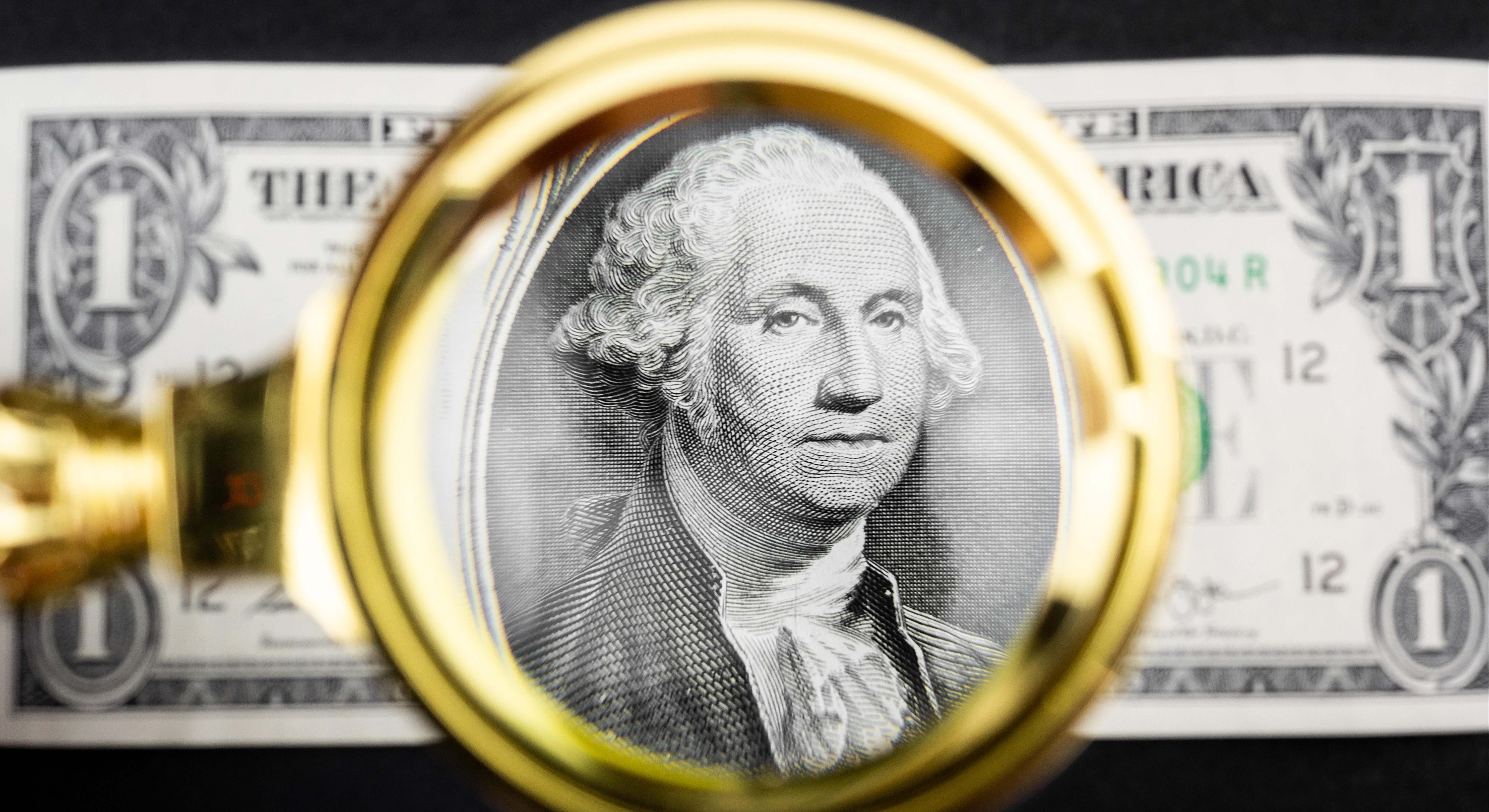 Una lupa amplía un dólar. Imagen: Alamy.