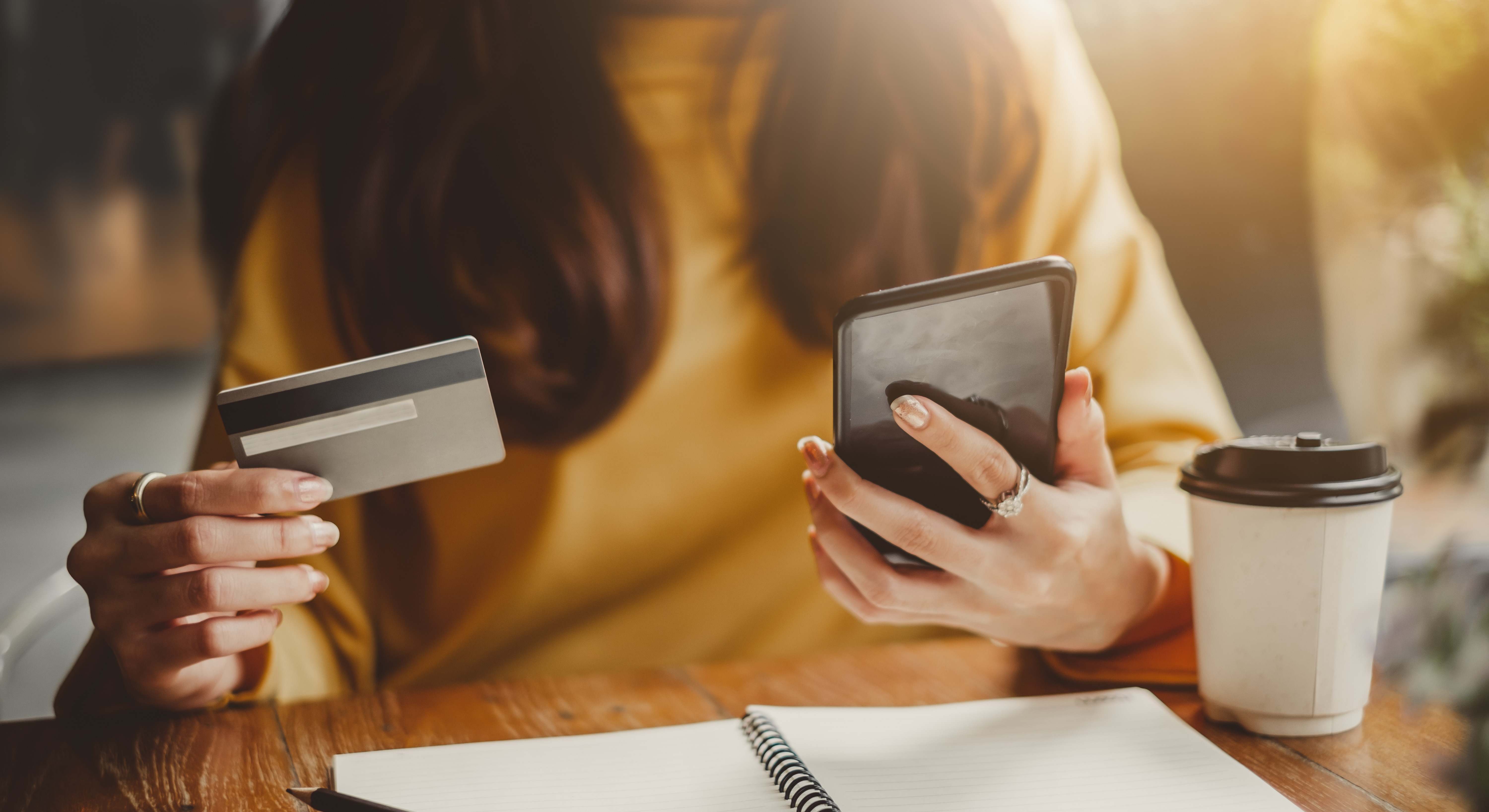 Mujer con un teléfono móvil y una tarjeta bancaria