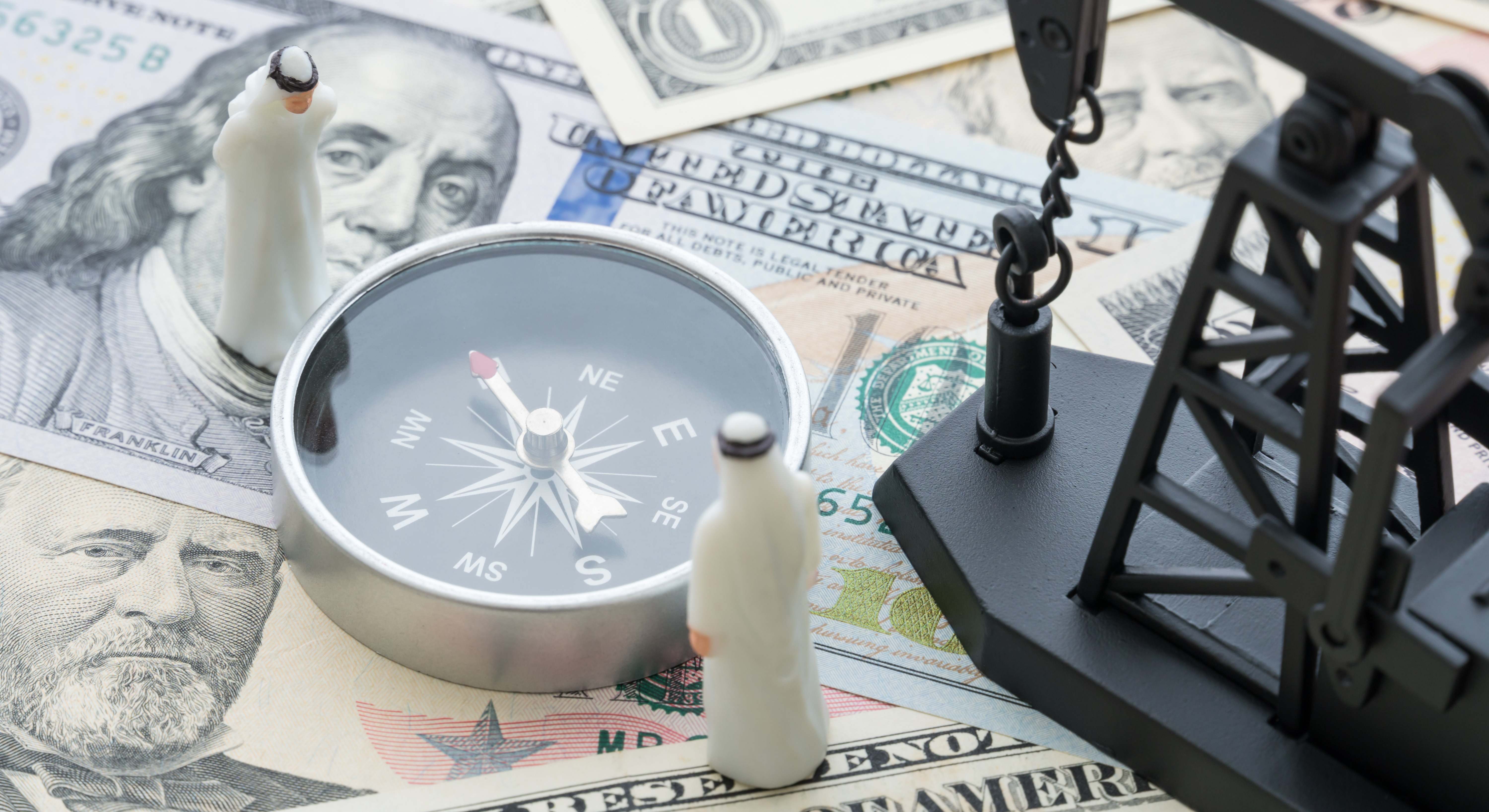 Una brújula unos árabes y una plataforma de petróleo sobre dólares