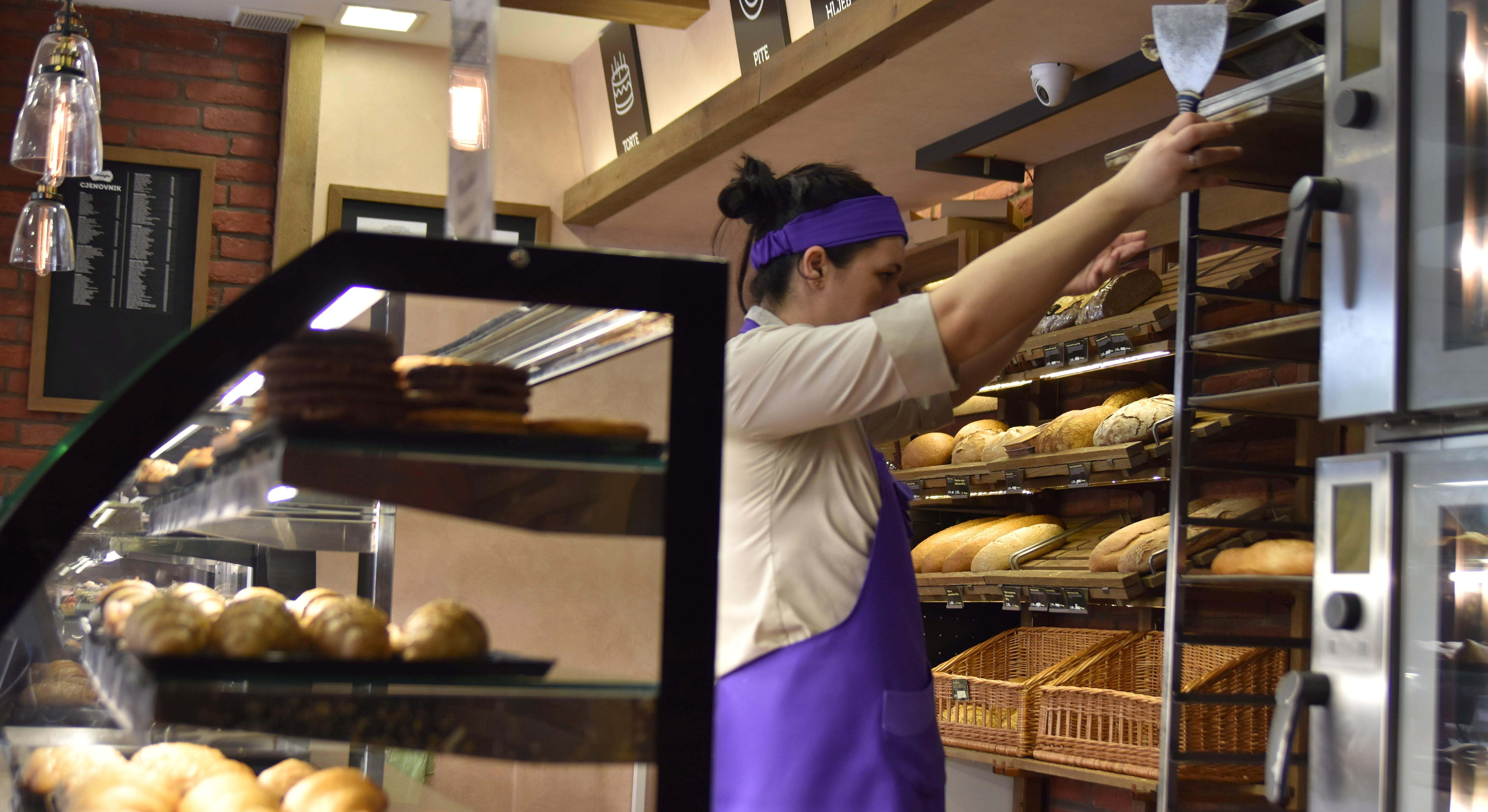 Mujer trabajando en un establecimiento de panes y dulces. Foto: Alamy