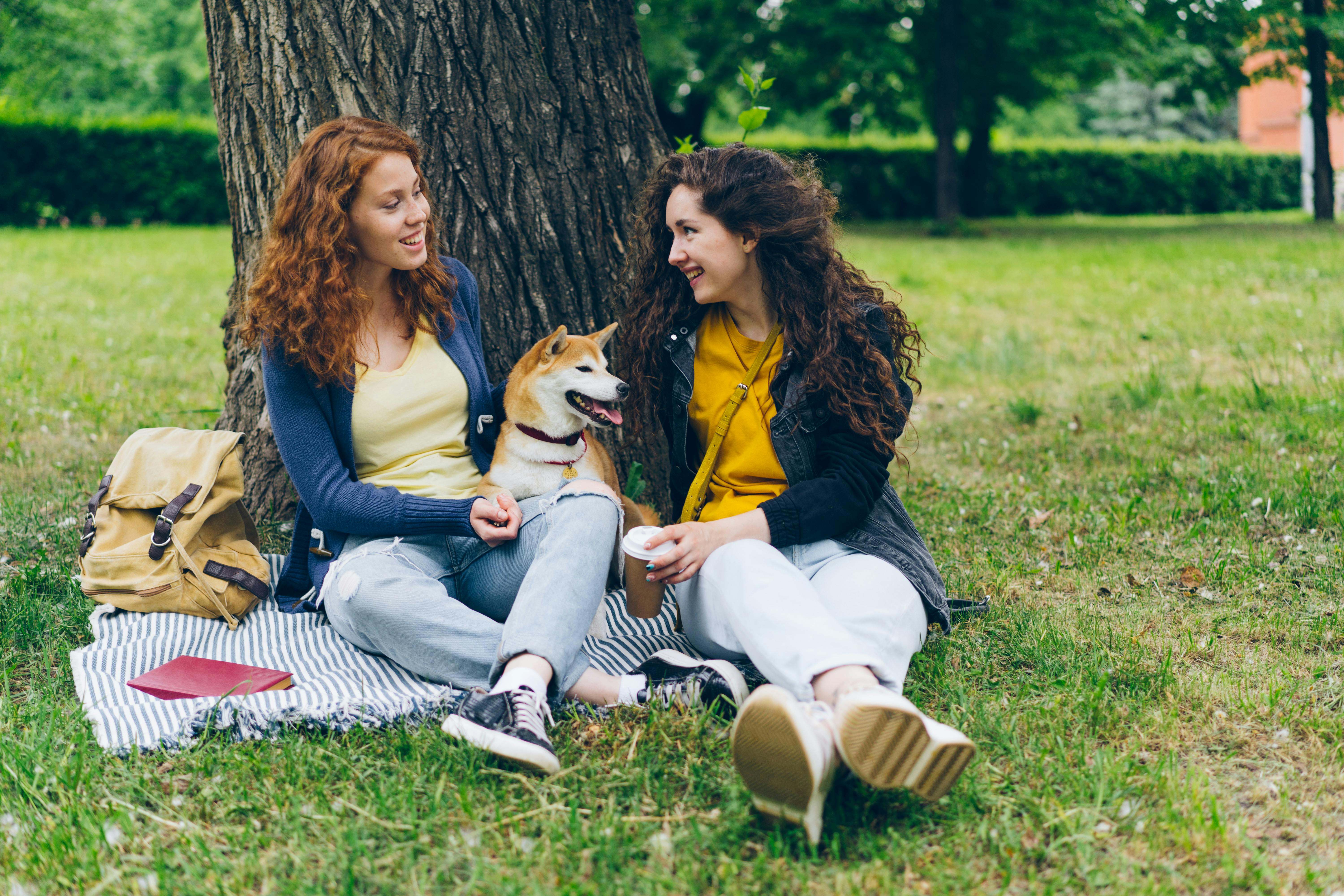 Dos mujeres se encuentran, junto a su perro, en un parque