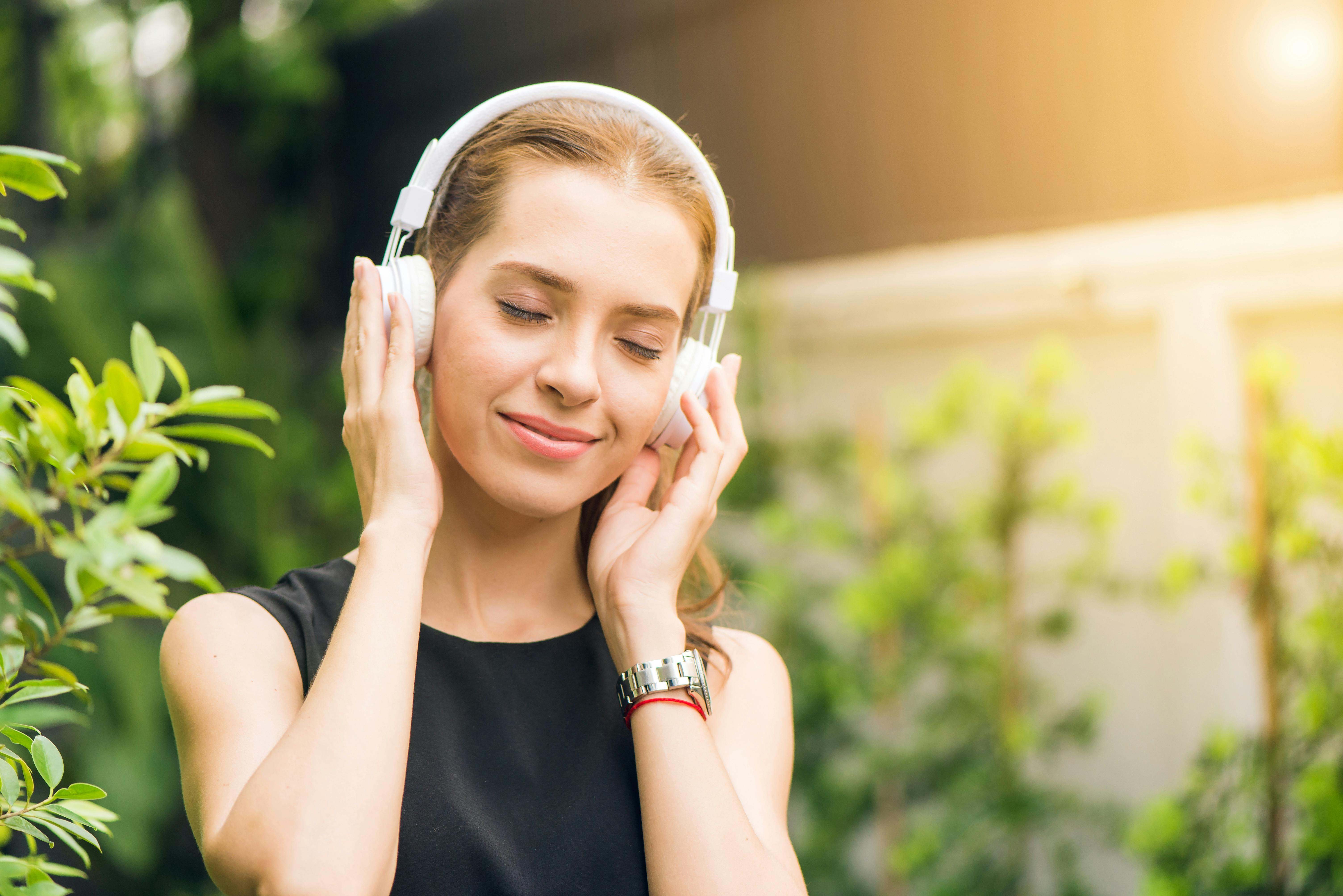 Una adolescente escucha música en el jardín de su casa