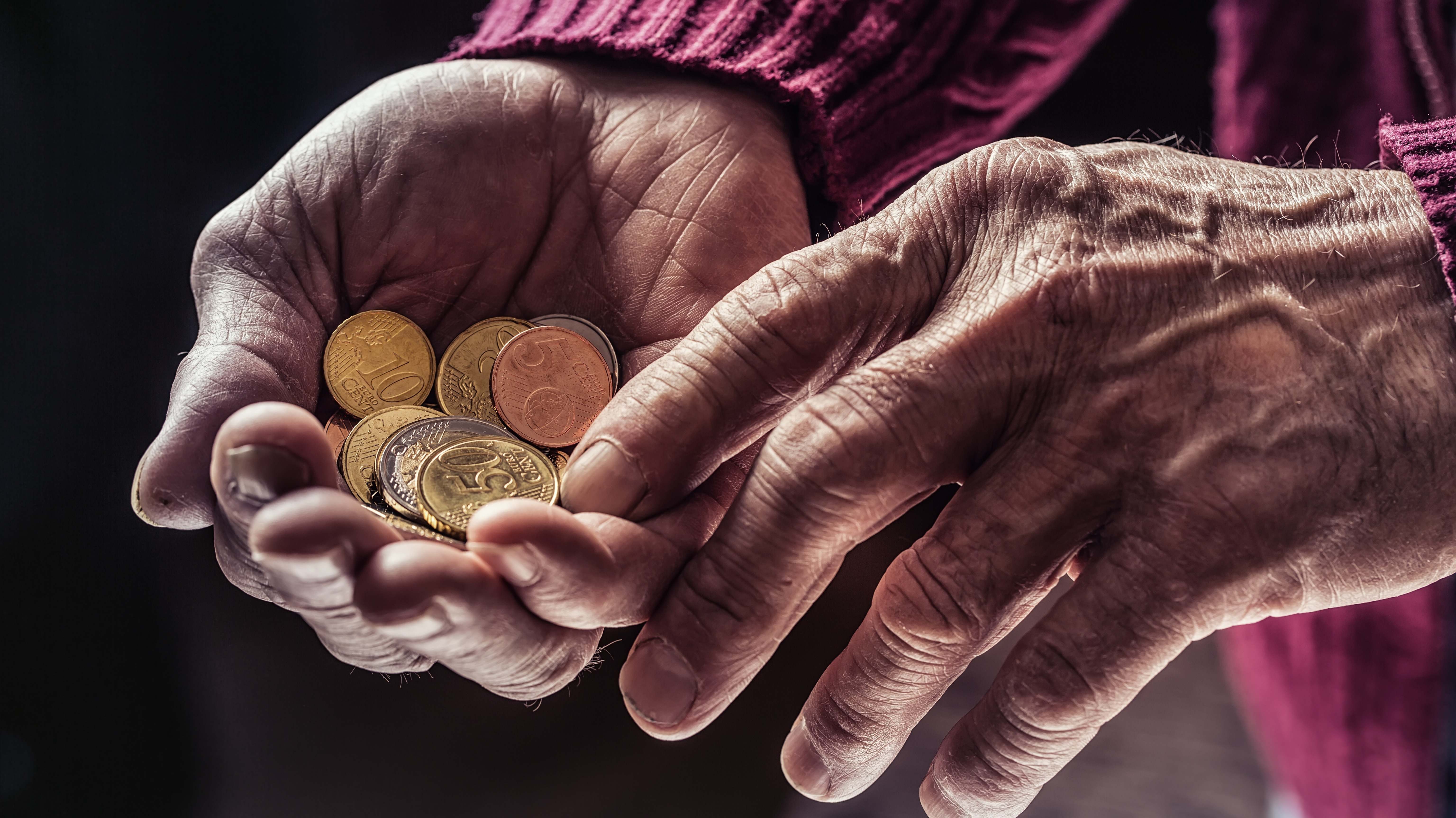 Una persona mayor contando monedas en la mano
