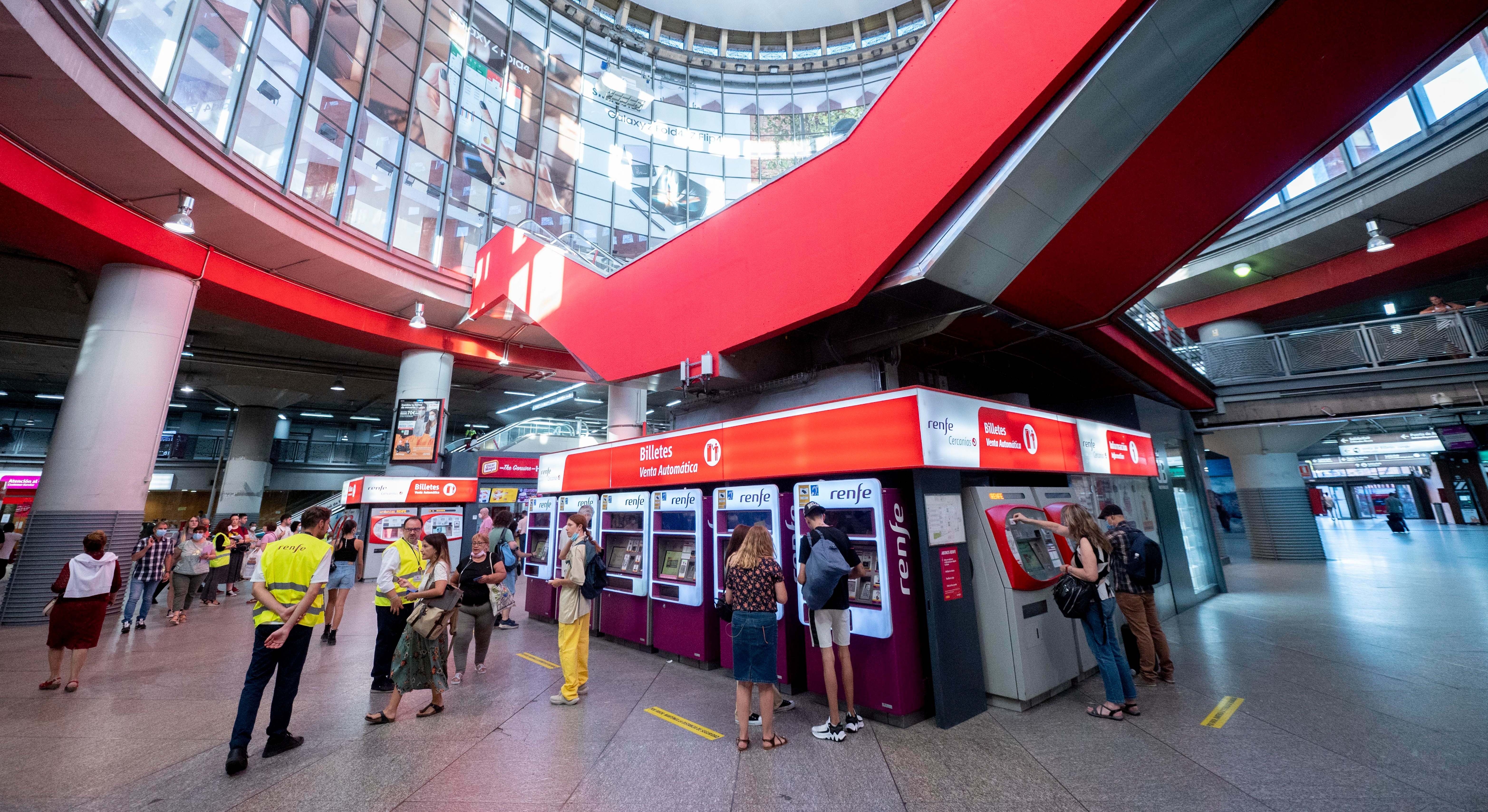 Varias personas en las taquillas de venta automática de billetes en la estación de tren de Atocha.