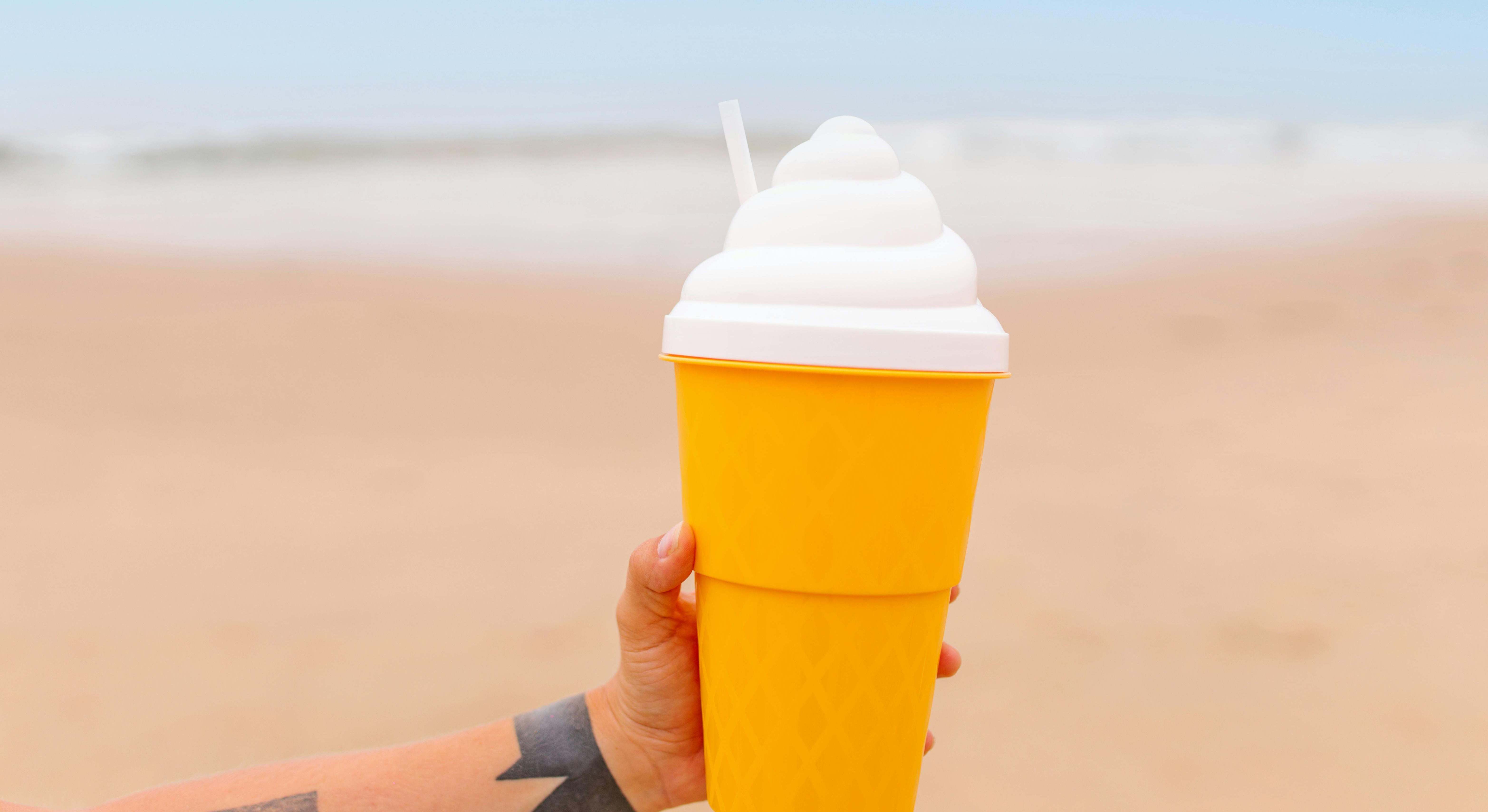 Un hombre sostiene un batido en la orilla de una playa