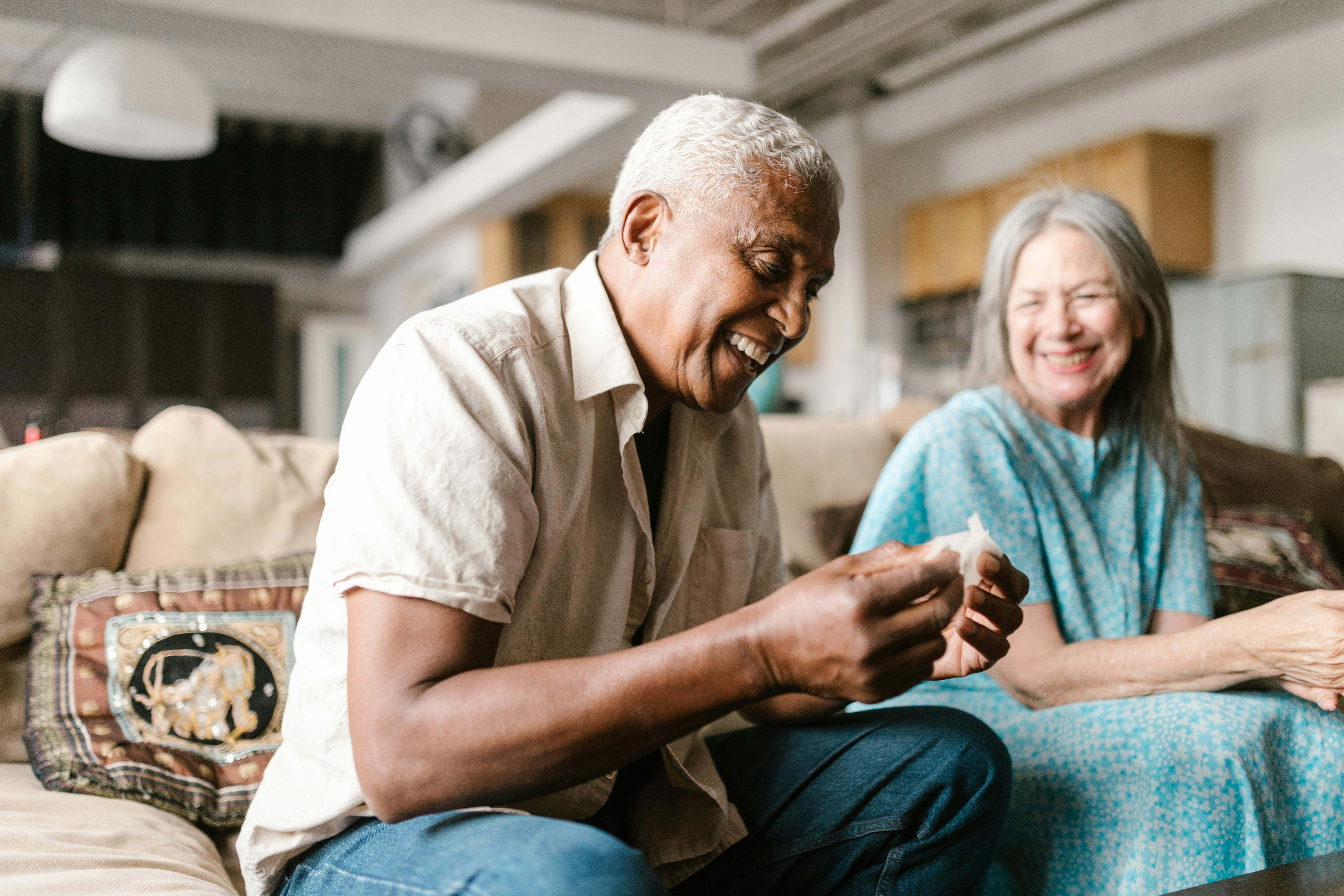 Una pareja de ancianos sonríe mientras juega a un juego de mesa