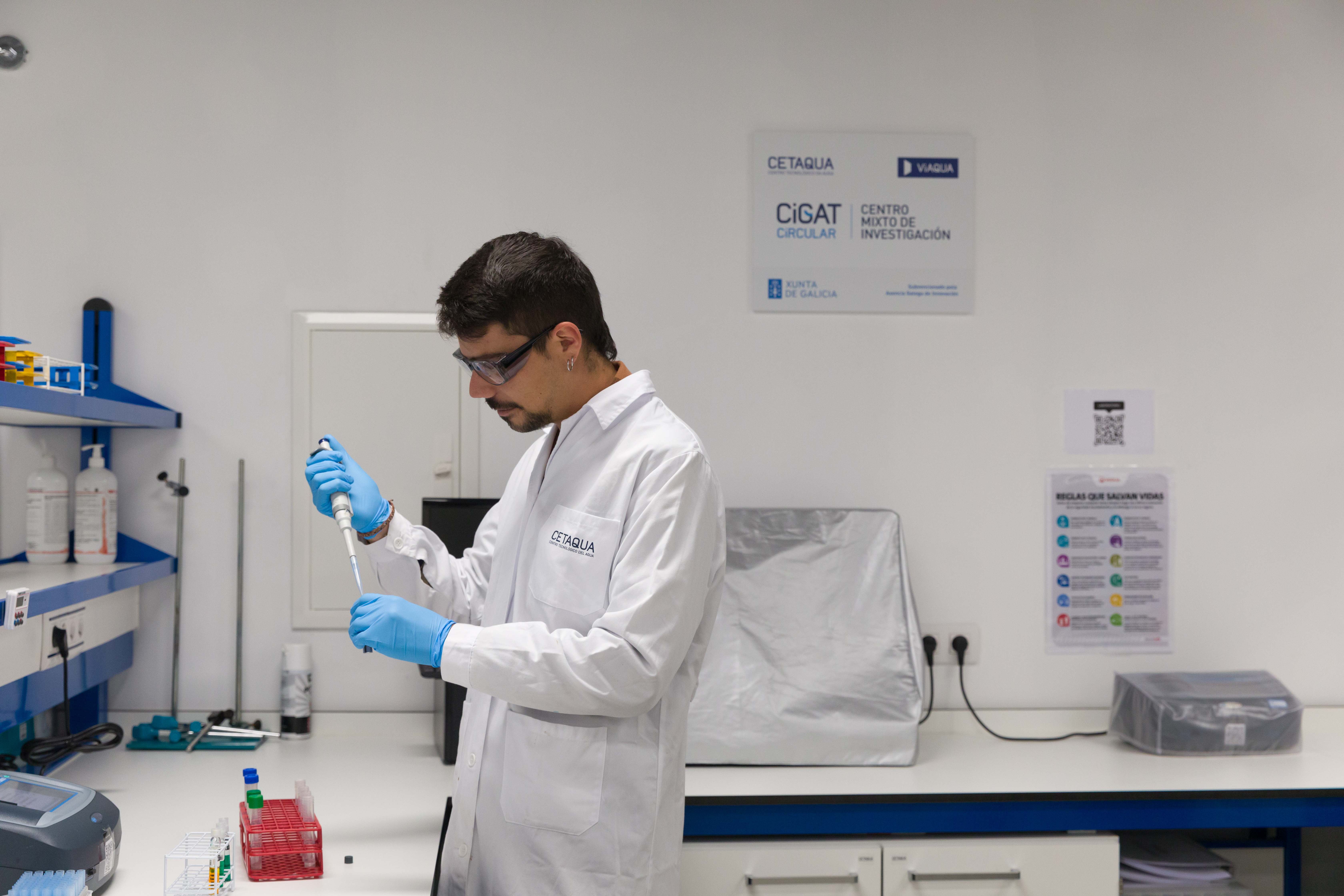 Hombre en laboratorio con bata blanca y una probeta