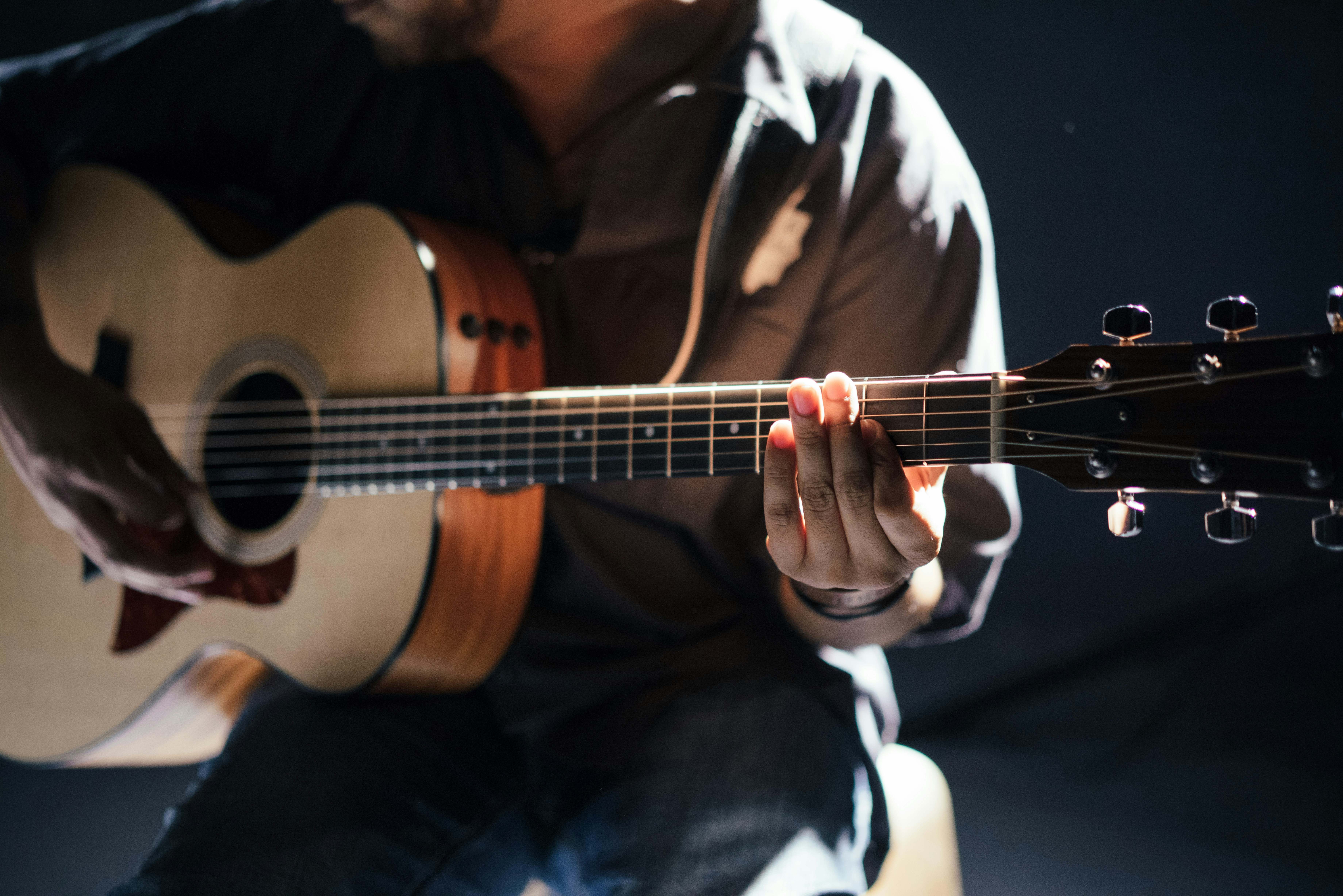 Un hombre toca la guitarra en una sala prácticamente a oscuras