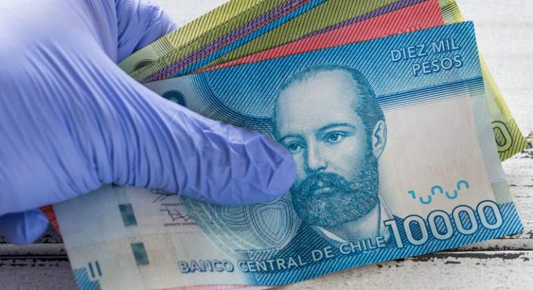 Una mano con guantes maneja billetes de pesos chilenos