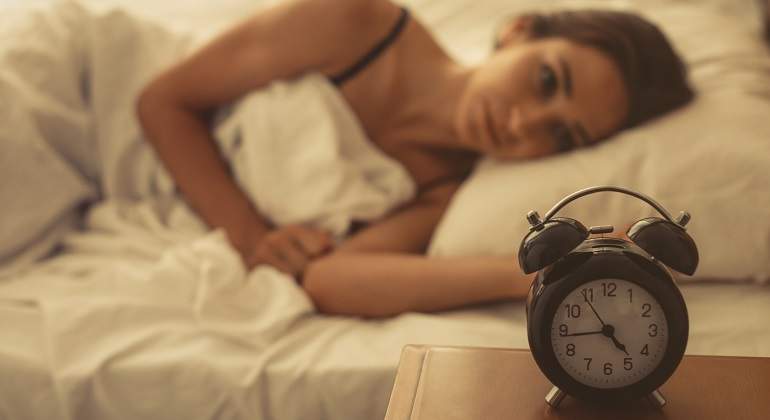 Una-mujer-despierta-tirada-en-cama-y-mirando-el-despertador-iStock.jpg