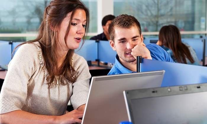 Estudiantes con un porttil en una biblioteca