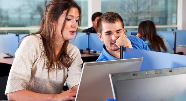 Estudiantes con un porttil en una biblioteca