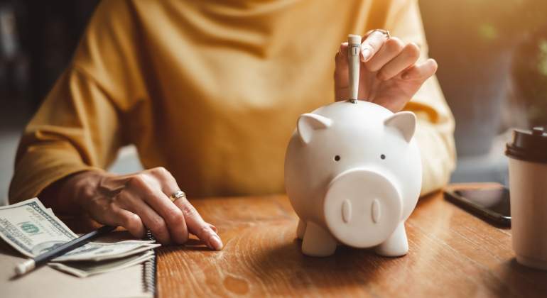 Una persona mete dinero en la hucha