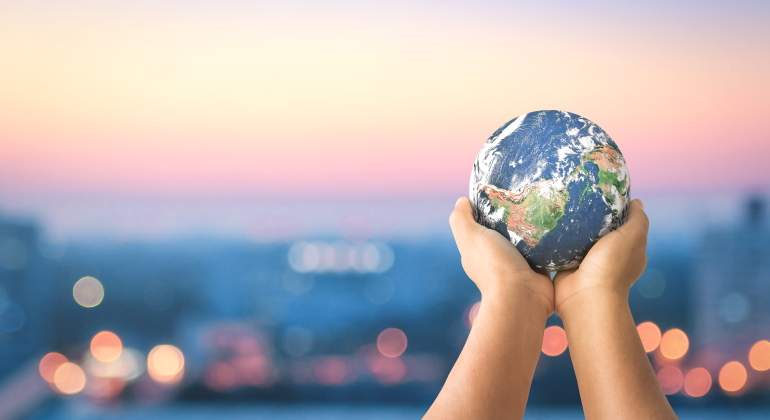 Unas manos sostienen el planeta con la ciudad al fondo