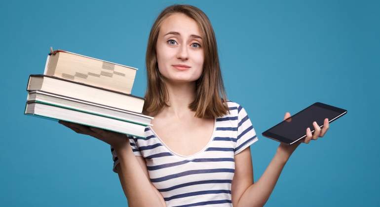 Una chica sostiene libros tradicionales en una mano y un ebook en la otra