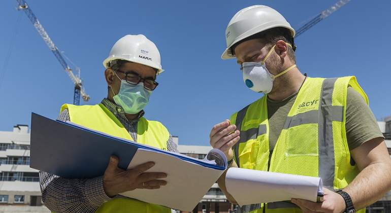 Dos trabajadores de Sacyr inspeccionan documentos en una obra