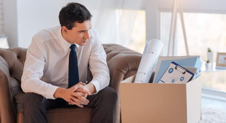 Un hombre mira serio a una caja con sus pertenencias tras perder su empleo