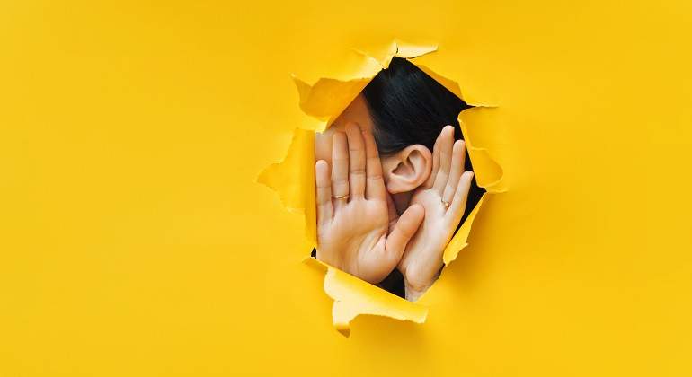 Una-mujer-mostrando-sus-manos-y-oreja-por-un-agujero-iStock.jpg