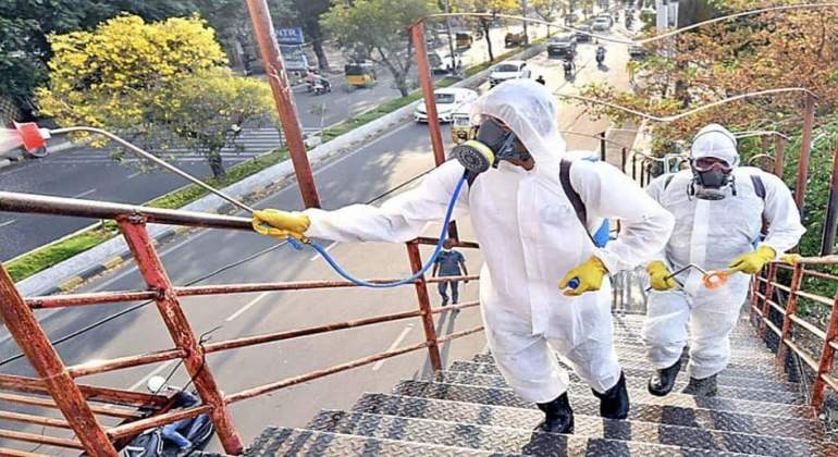 Unos trabajadores suben las escaleras de un inmueble para desinfectarlo