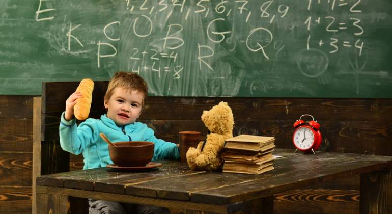 Un nio come en su pupitre en la escuela