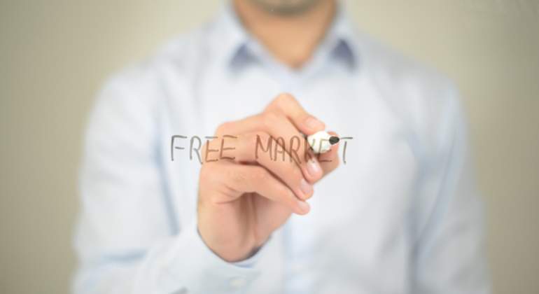 Un hombre escribe free market con un rotulador