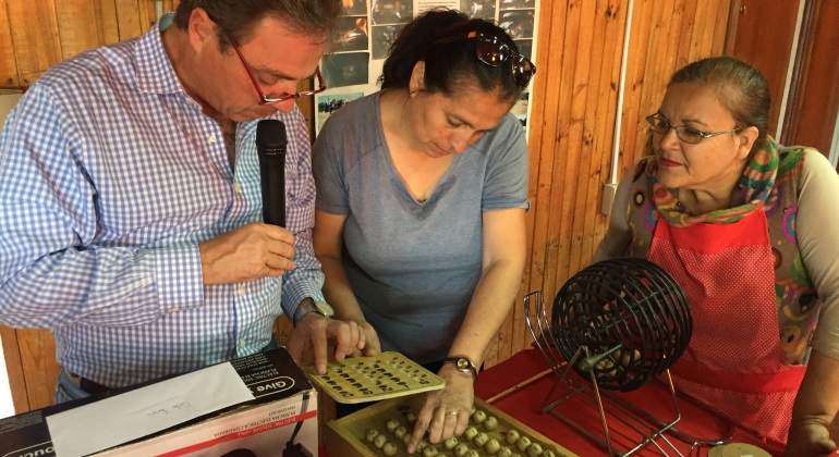 Un hombre lee los nmeros del bingo en presencia de dos mujeres