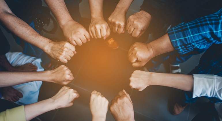 Varias personas unen sus manos para trabajar unidas