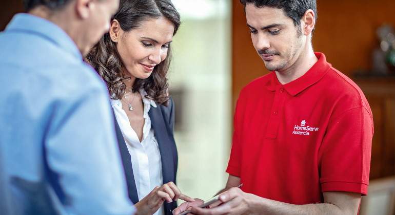 Un trabajador de la empresa de reparaciones HomeServe atiende a dos clientes