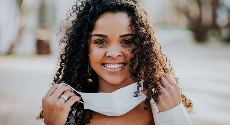 Una-chica-morena-con-el-pelo-rizo-poniendose-la-mascarilla-iStock.jpg