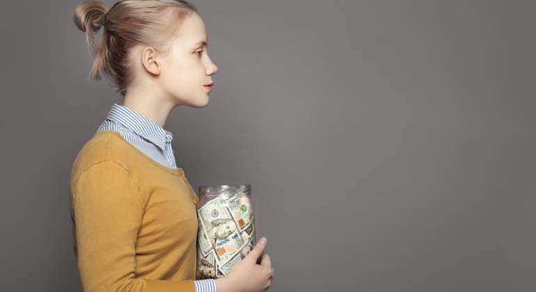Una mujer sostiene un frasco lleno de dinero