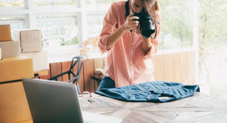Una mujer fotografa una prenda para subirla a su web de comercio online