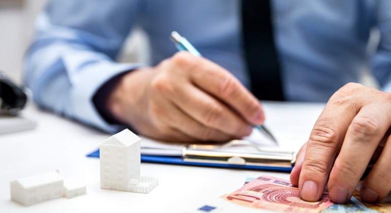 hombre-firma-dinero-casitas-istock.jpg